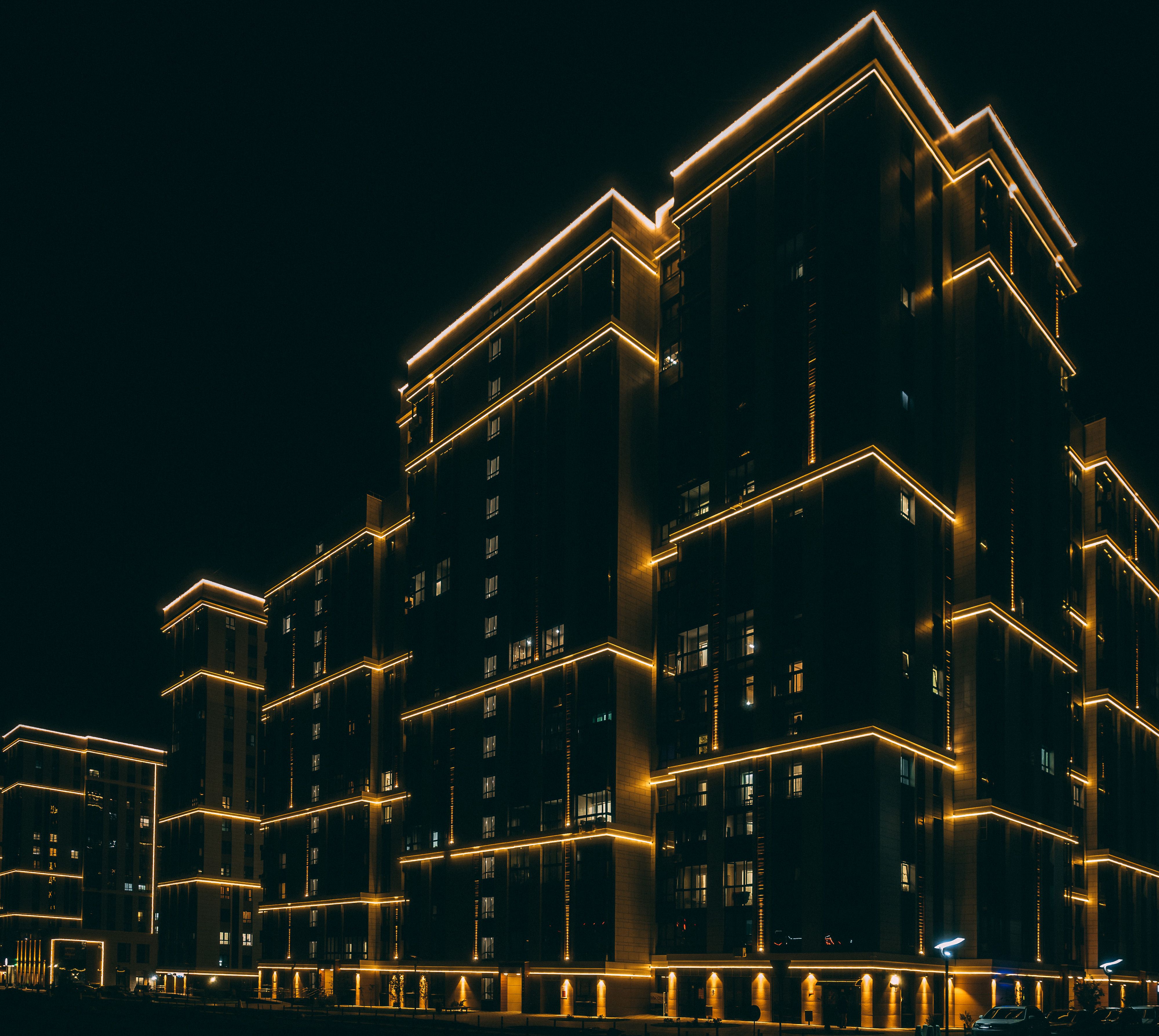 Night city. Modern residential multi-storey house with illumination. urban infrastructure. Glow-in-the-Dark Luxury Residential Complex Beautiful Background.