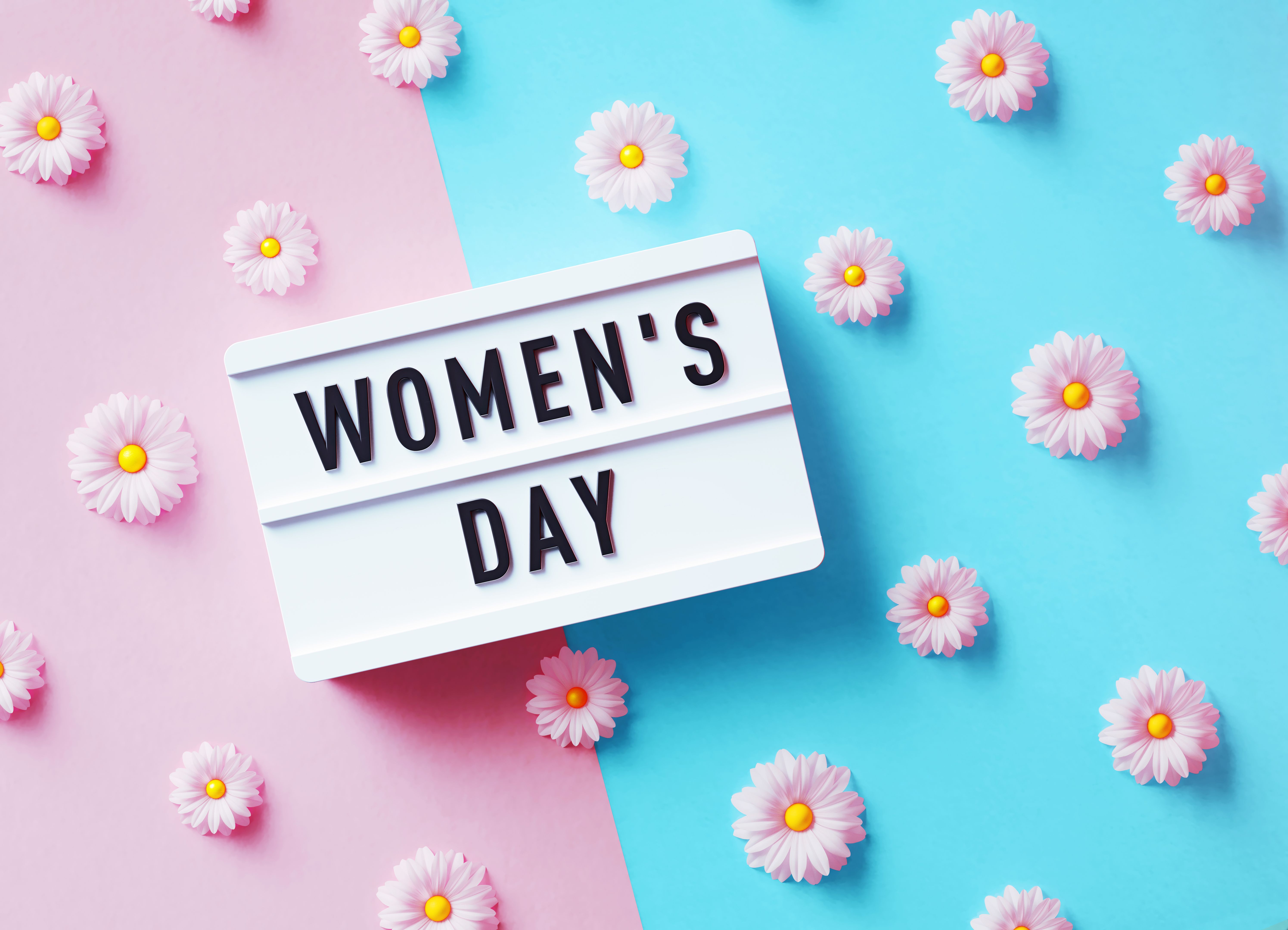 Women's Day Concept - Women's Day Written White Lightbox Sitting Amidst Daisies On Pink And Blue Background