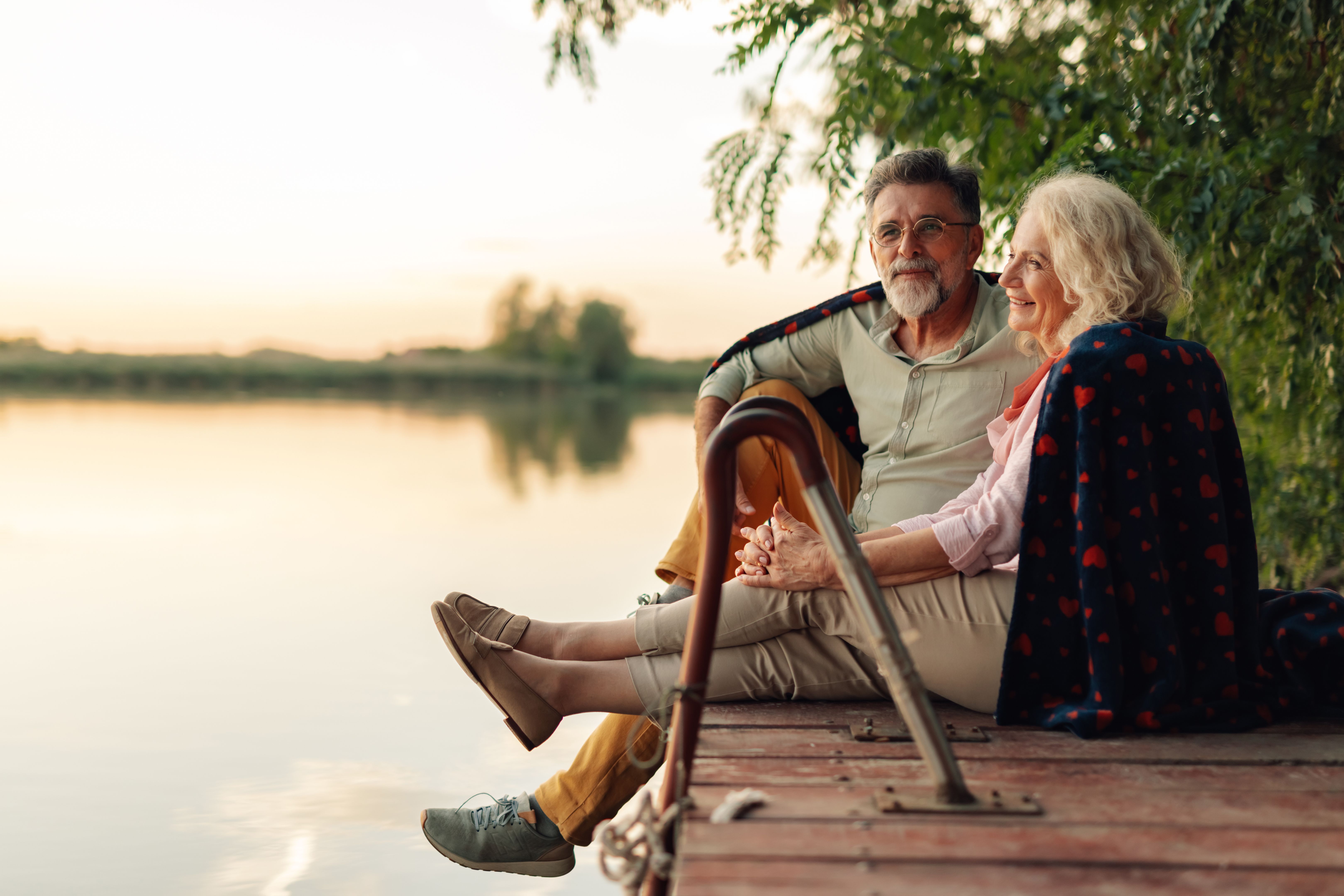 Senior couple holding hands and enjoying a serene sunset by the lake