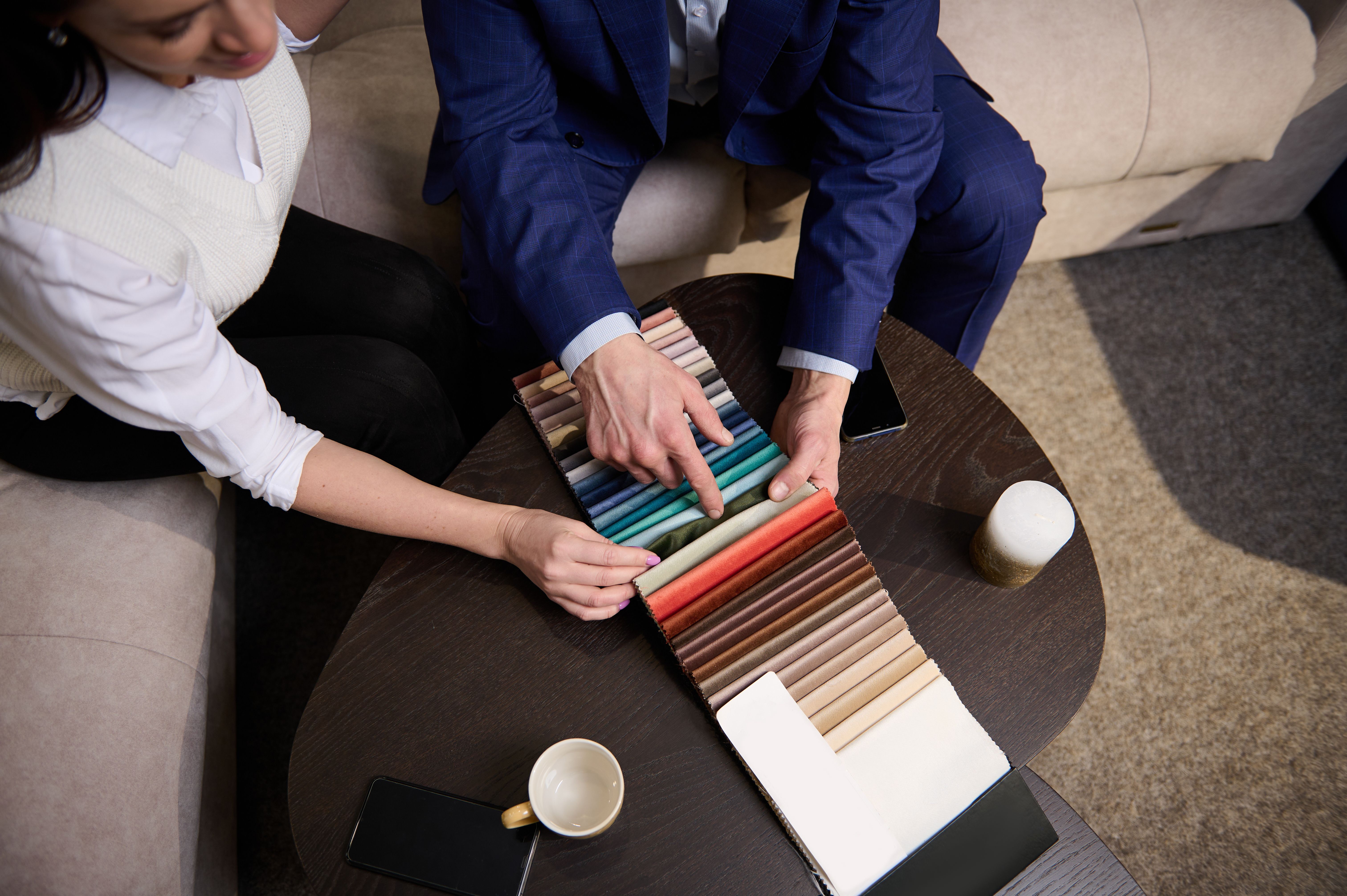 Focus on samples of colored fabrics for upholstered furniture. Top view of couple choosing color and fabric texture for upholstery sofa in the home. Interior design concept Focus on samples of colored fabrics for upholstered furniture. Top view of couple choosing color and fabric texture for upholstery sofa in the home. Interior design concept