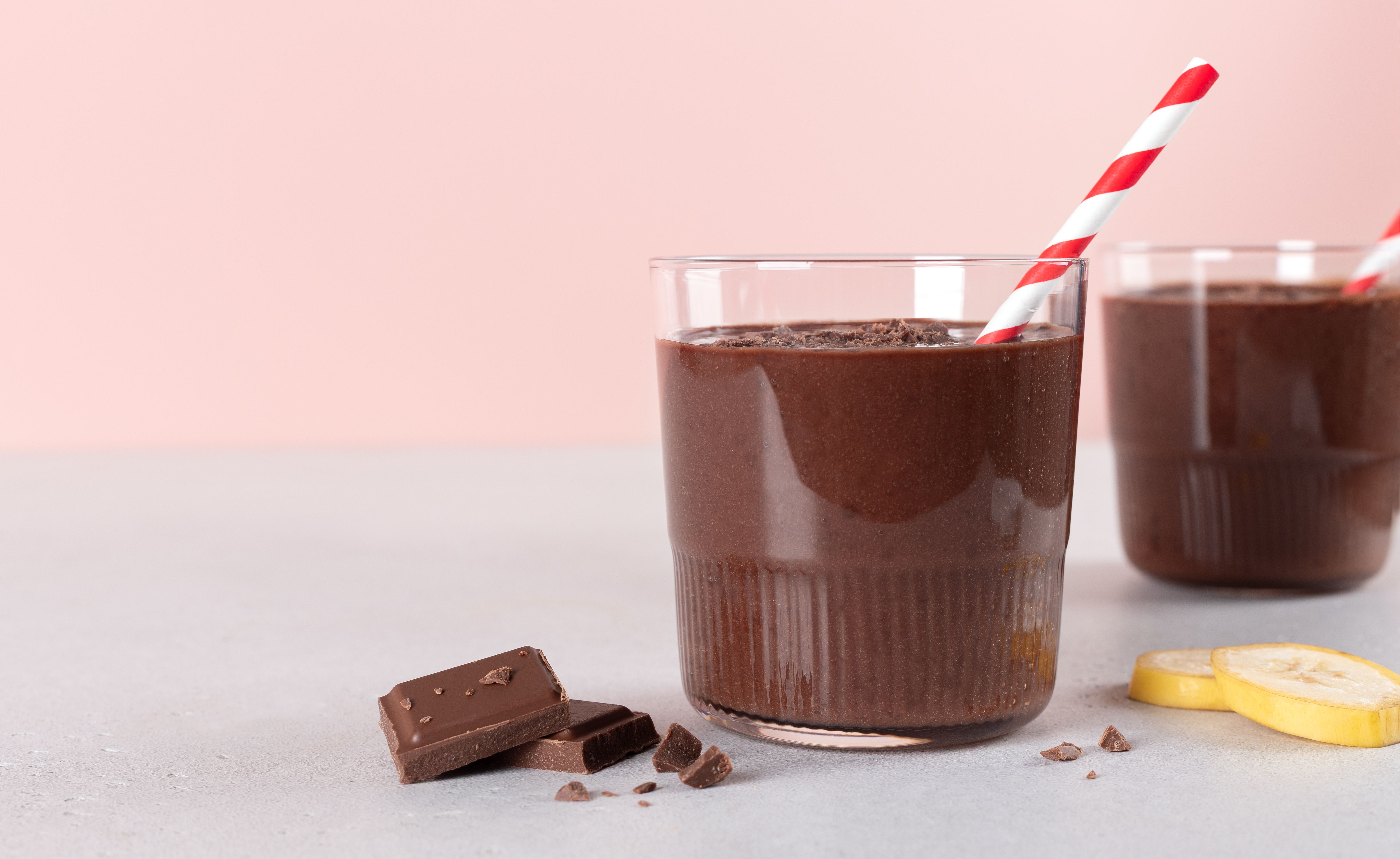 Chocolate banana smoothie on pink background. Copy space.