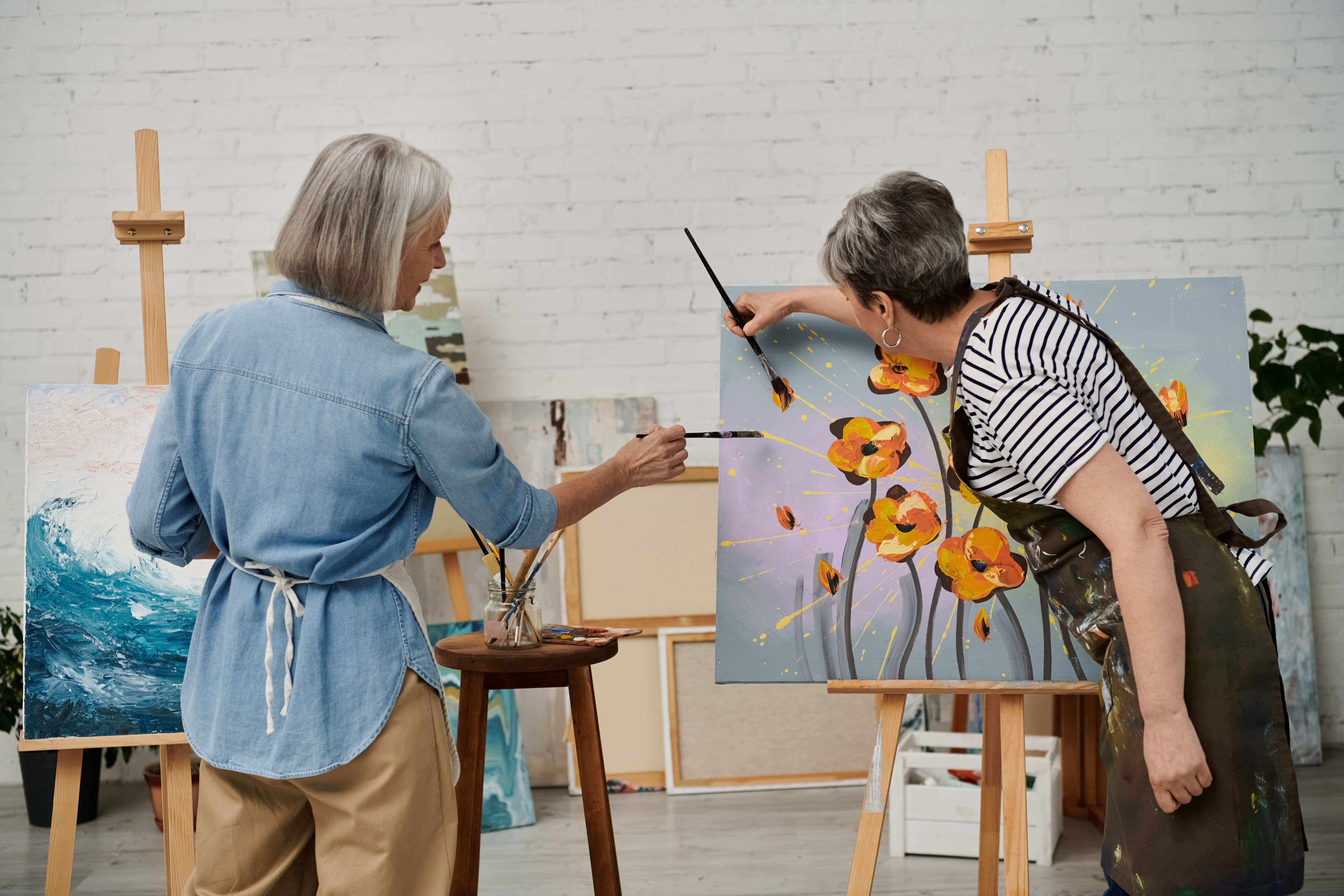 Mature lesbian couple enjoying art together while painting in a cozy studio space