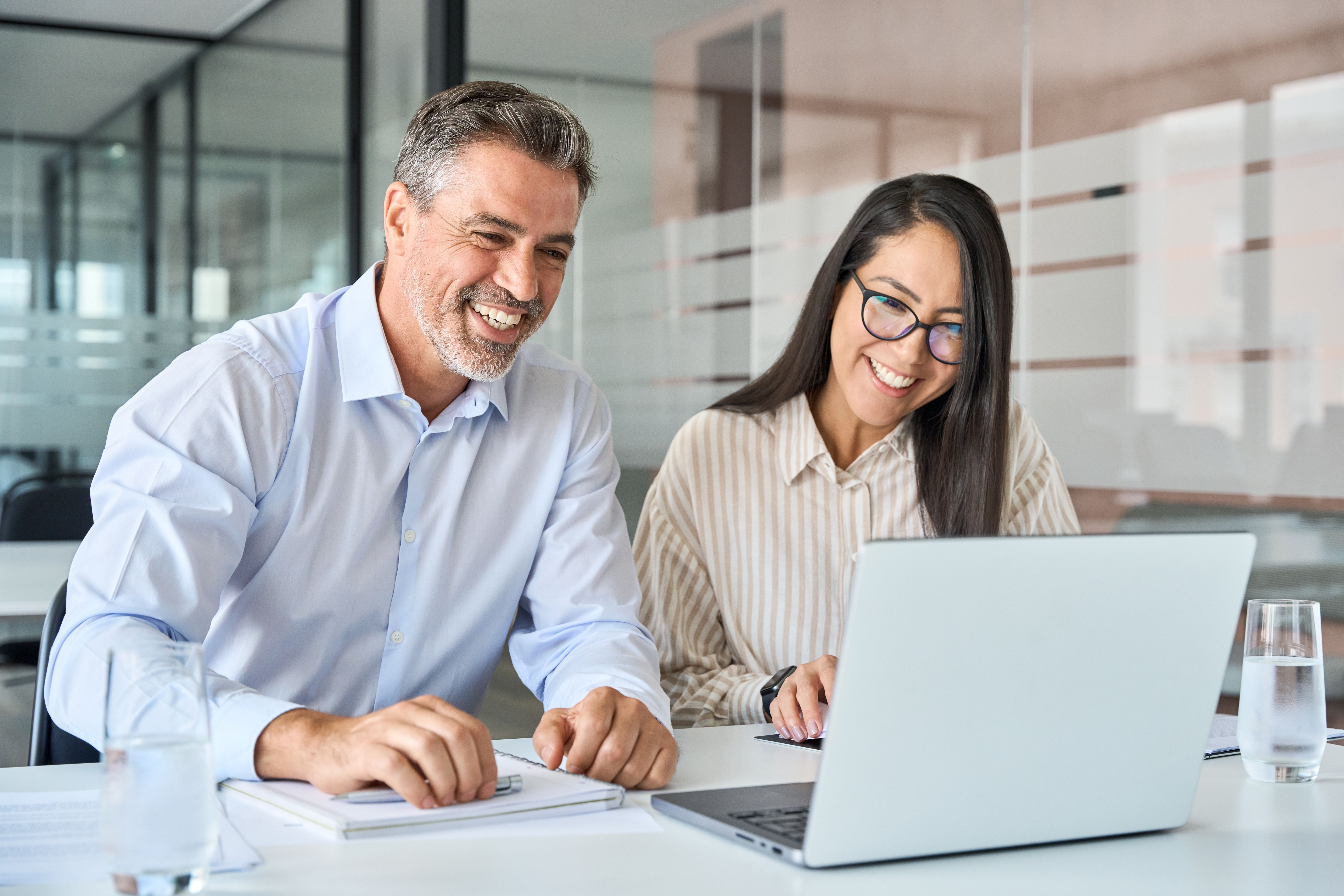 Smiling couple looking at laptop, representing the hopeful action of scheduling an online consultation to find their Emerging Strength