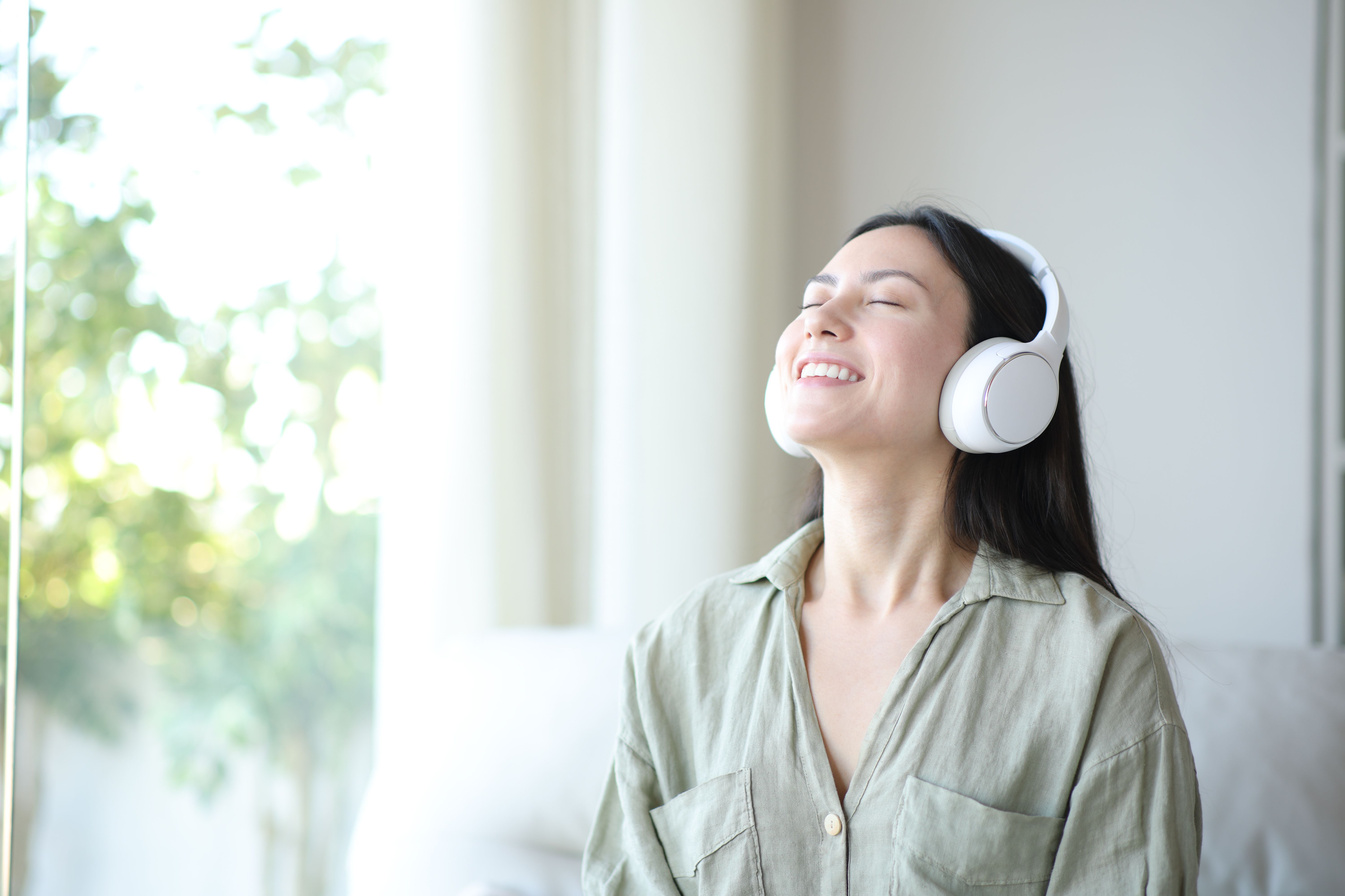 Happy asian woman breathing wearing headphone at home