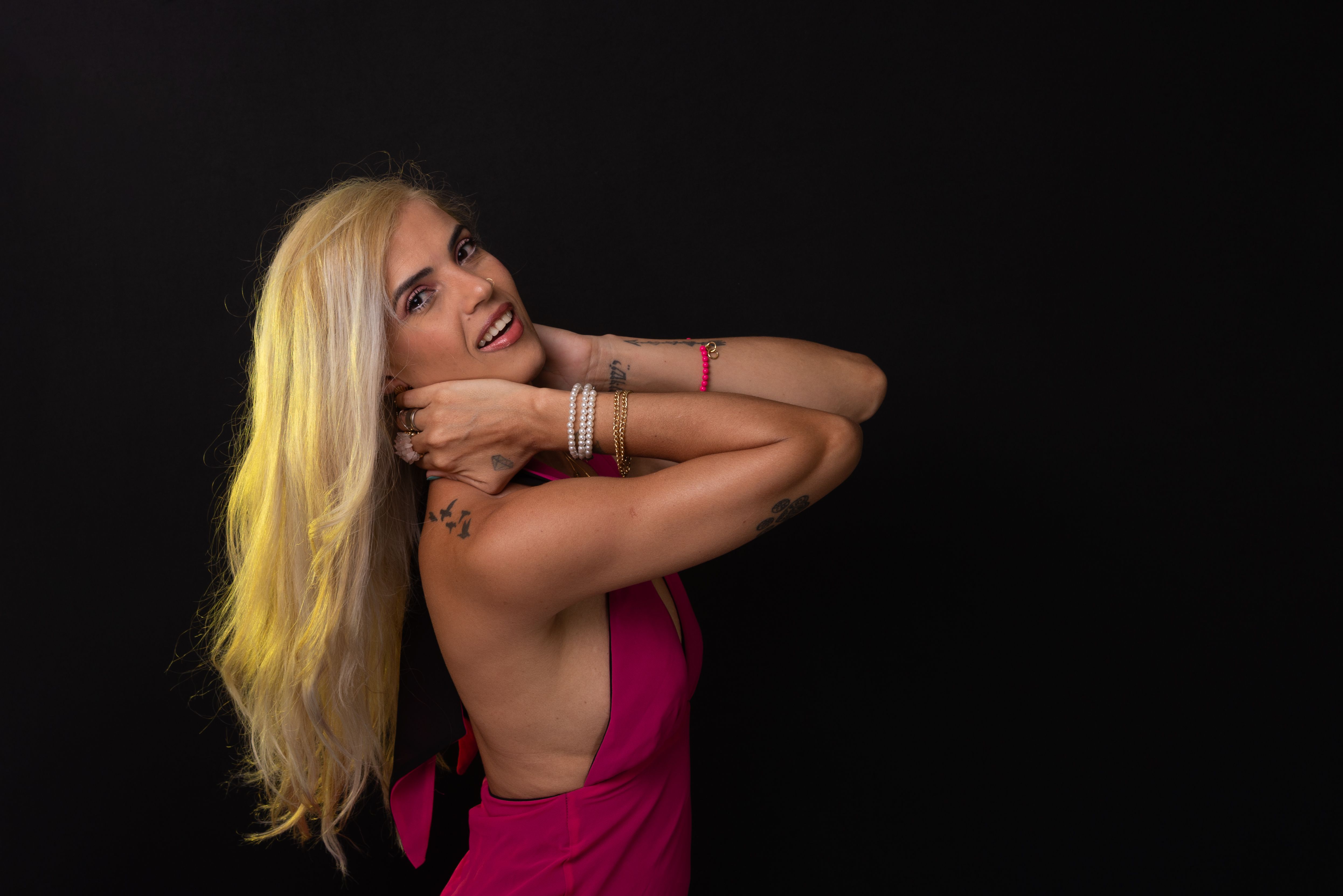 beautiful caucasian woman with blond hair in red dress posing and looking at camera isolated on black background. Studio in the city of Salvador, Bahia.