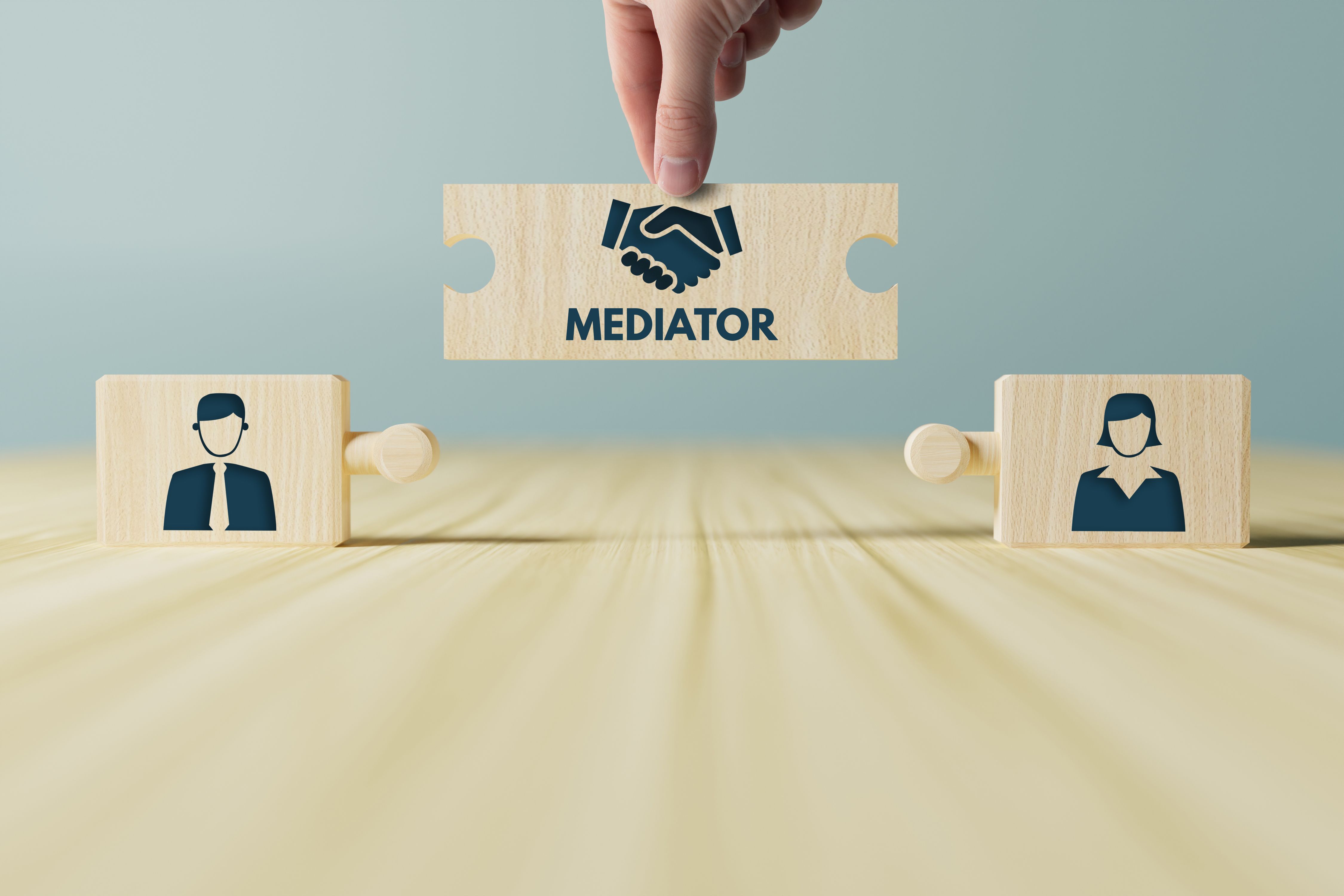 The hand holds wooden wooden blocks with icons of a woman and a man and shaking hands in the act of consent.