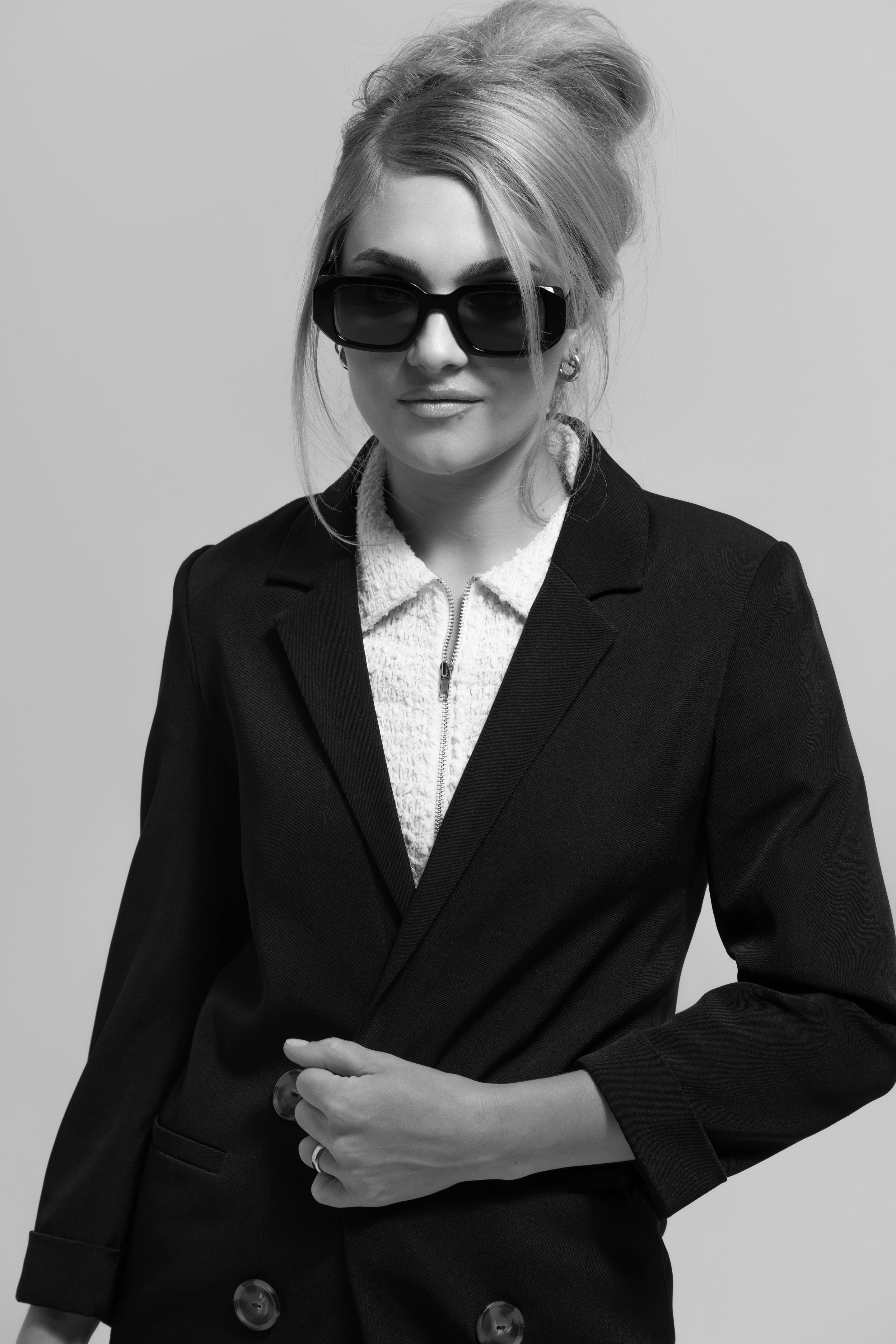 Beautiful woman with black suit and sunglasses black and white studio portrait portrait