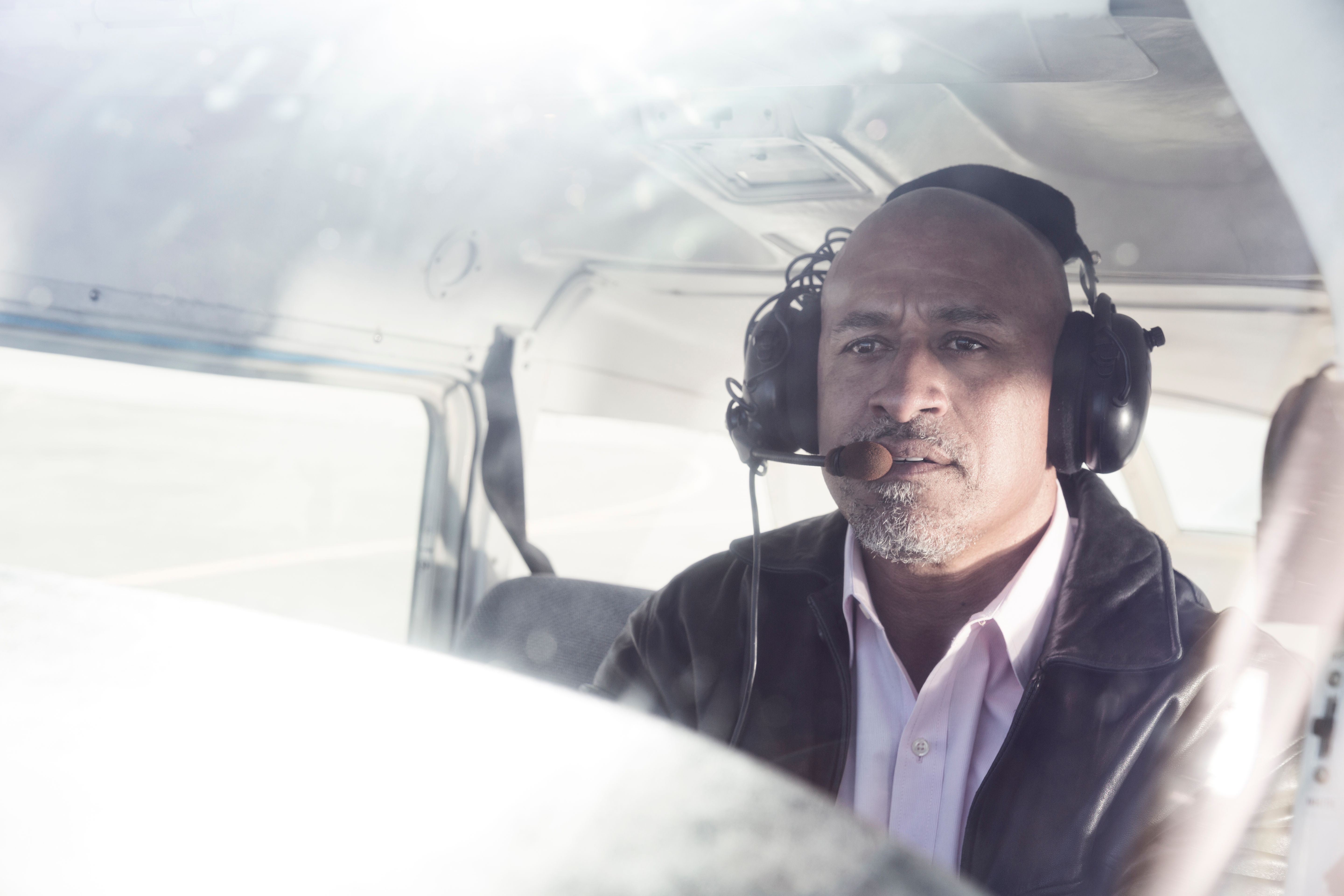 Serious pilot in cockpit of small plane wearing radio headset
