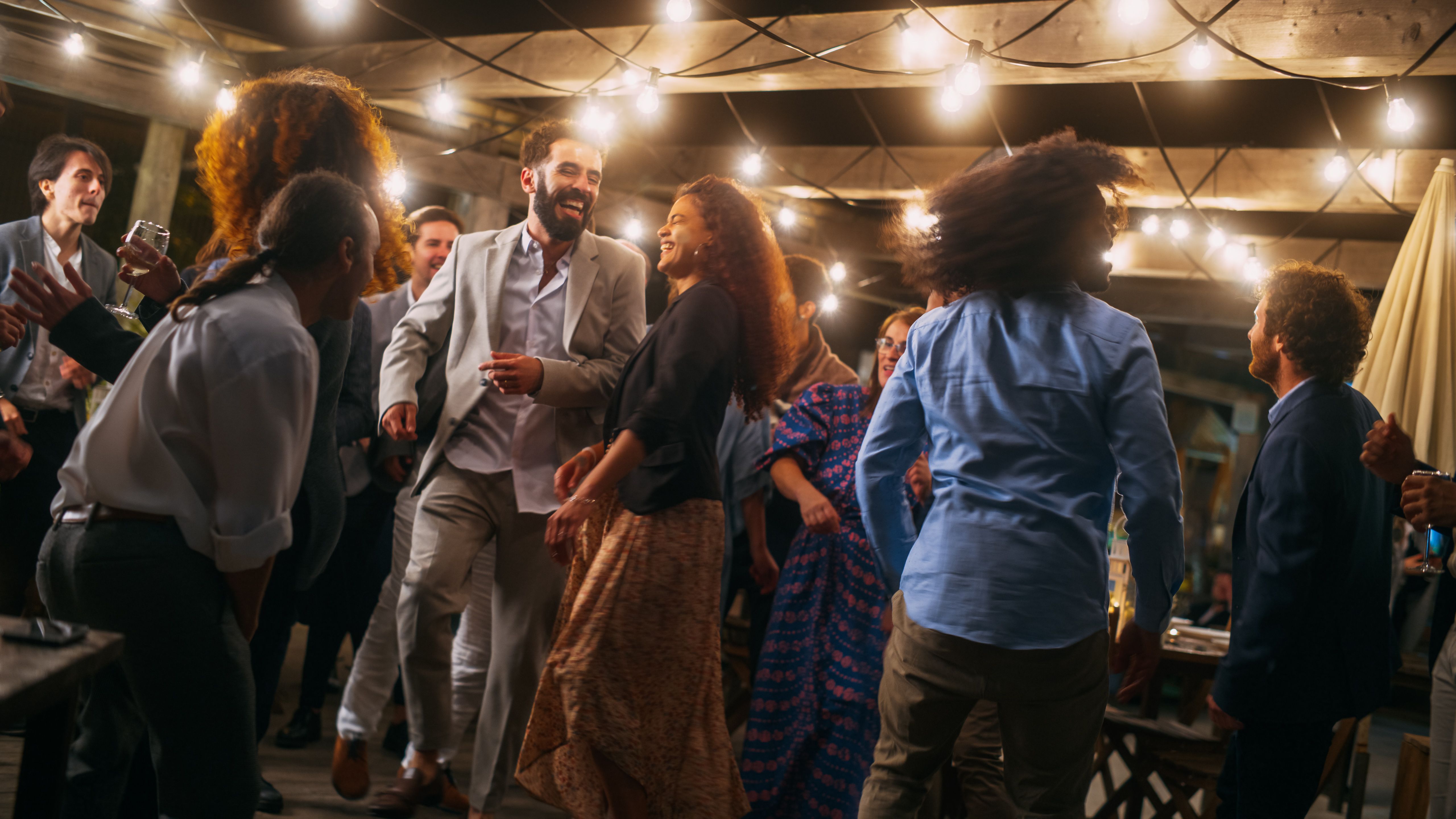 Beautiful Carefree Friends are Dancing Together and Celebrating an Evening Event at a Party . Diverse Multiethnic Young Adult People Have Fun at a Corporate Party in a Restaurant.