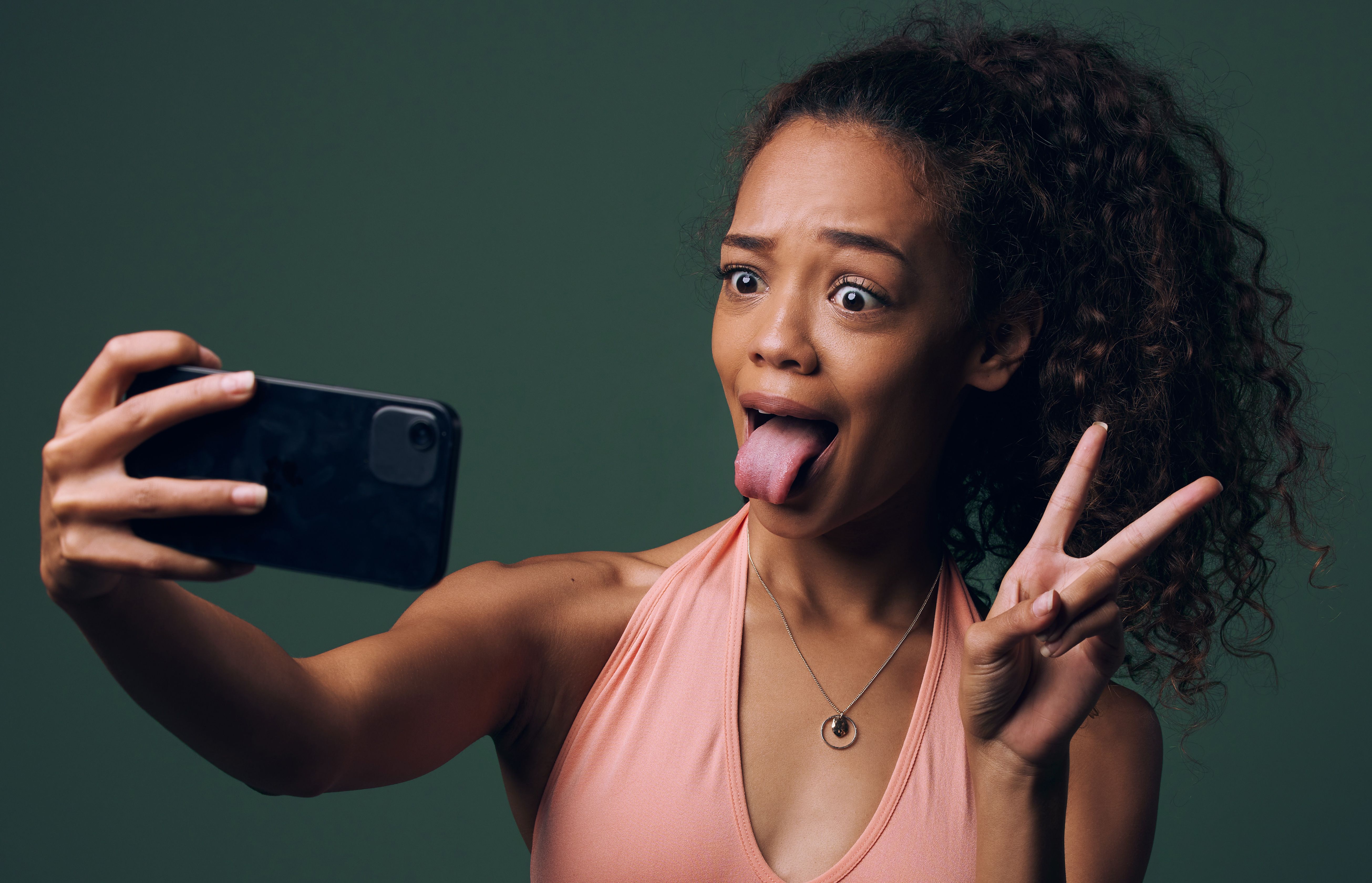 Cropped shot of an attractive and quirky young woman posing against a green background in studio