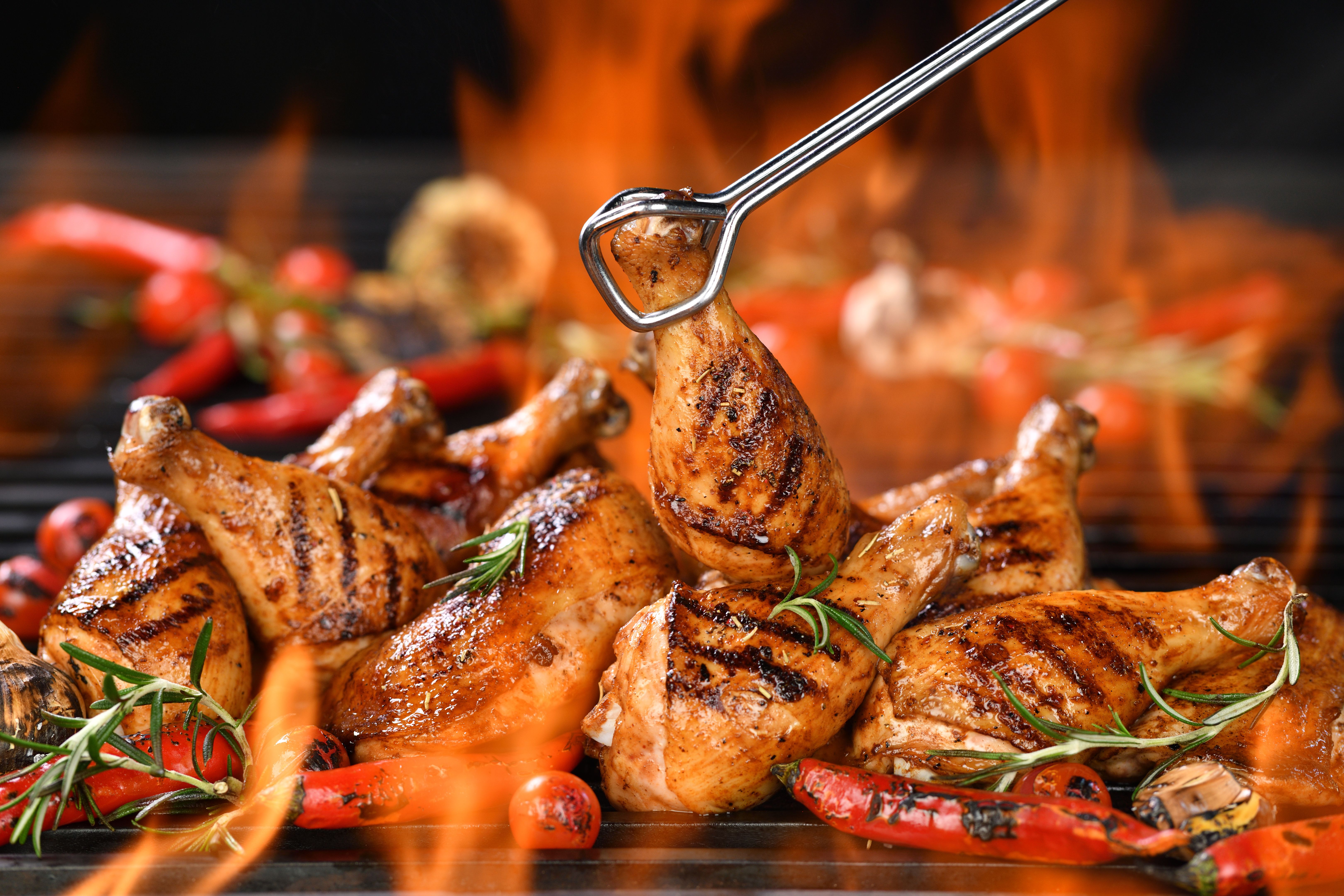 Grilled chicken legs and chicken thighs on the flaming grill