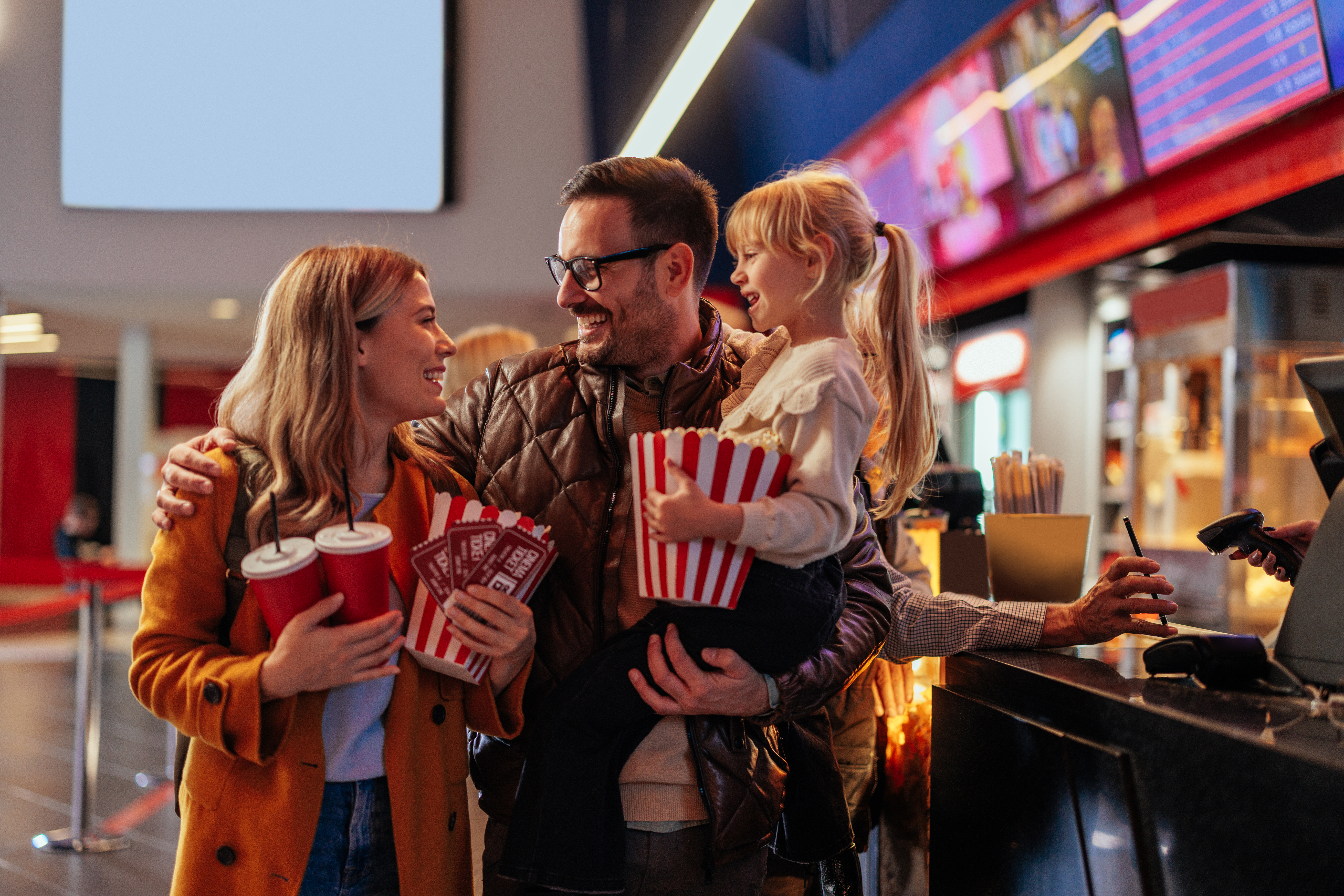 Cheerful parents with child in movie theater. Cheerful parents with child in movie theater.
