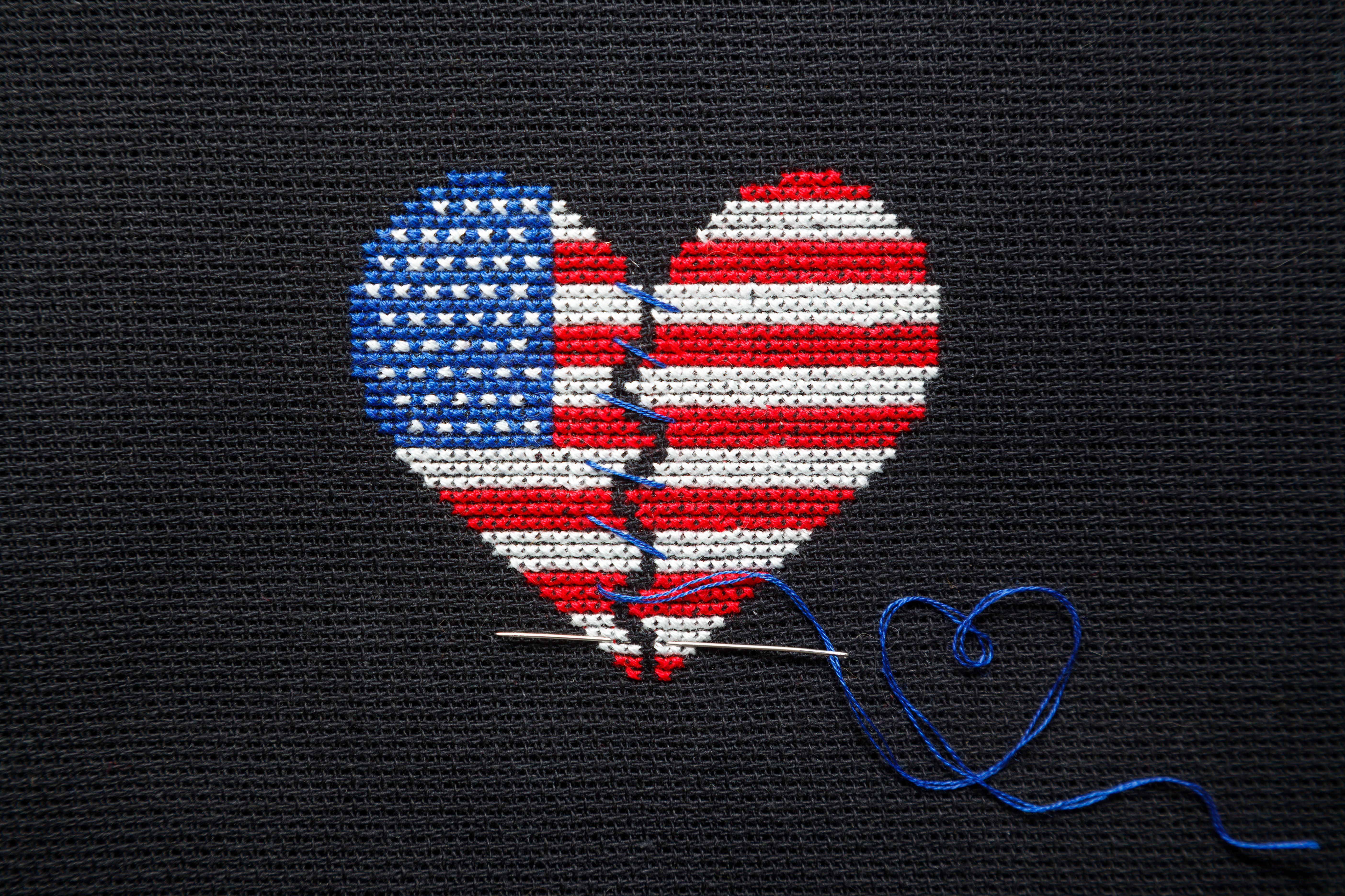 Broken heart of US flag colors embroidered on black canvas.