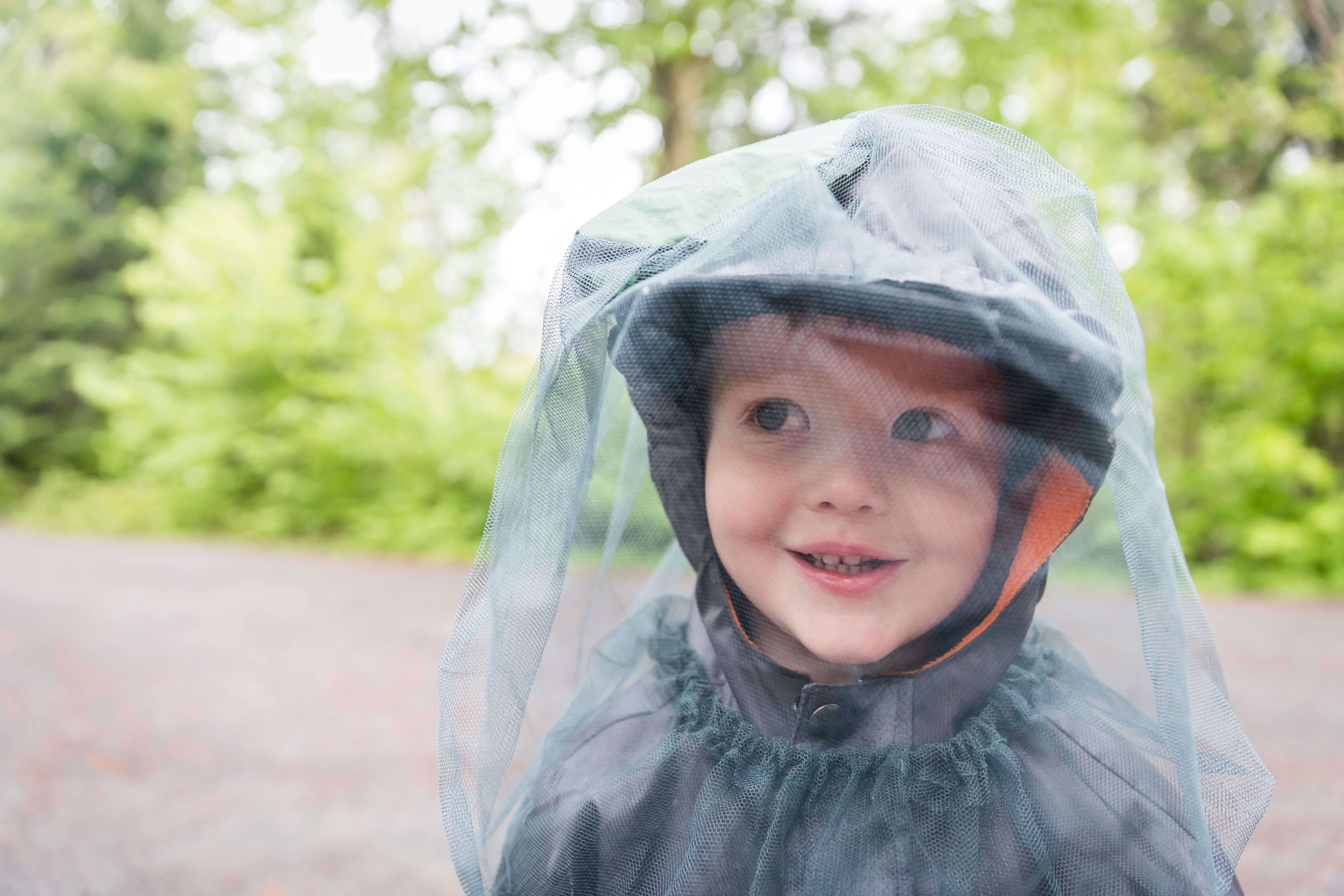 Pequeño niño pelirrojo jugando al aire libre en el camping y usando sombrero de mosquitera Pequeño niño pelirrojo jugando al aire libre en el camping y usando sombrero de mosquitera