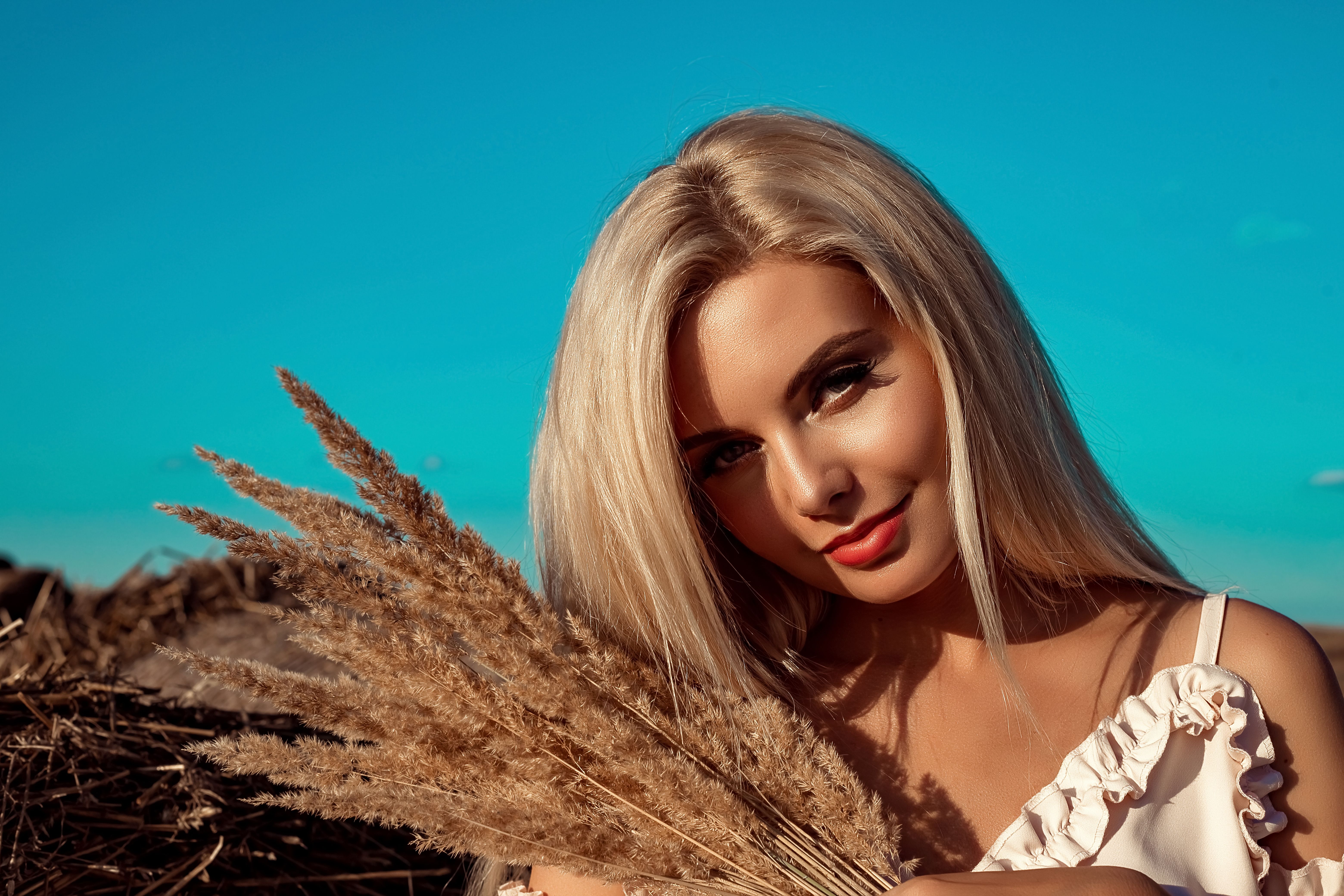 Portrait of a beautiful girl, blonde with long hair in a field a sunny day at sunset.