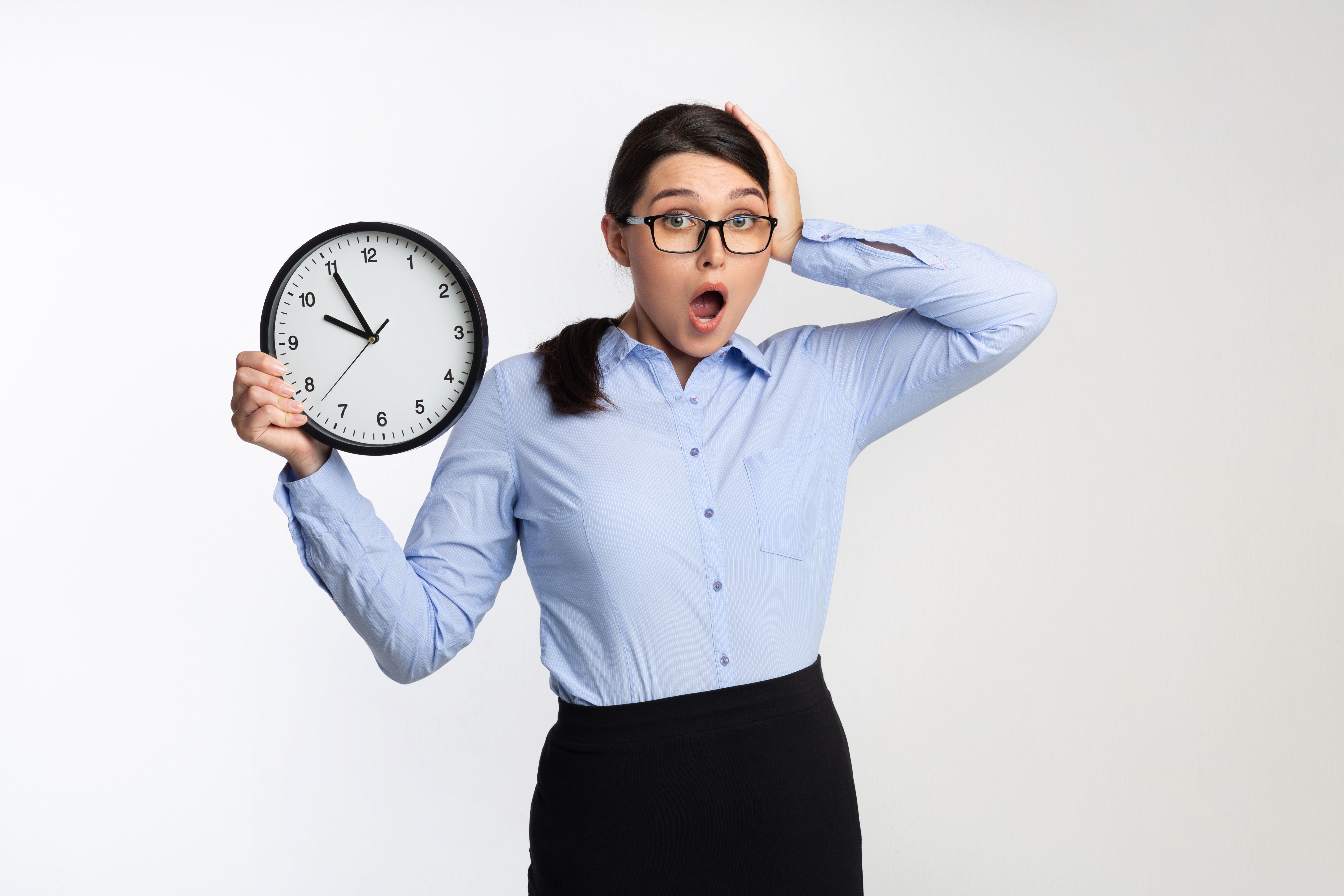 Woman in Business Attire Looks Surprised Holding a Clock Indicating Late Time Woman in Business Attire Looks Surprised Holding a Clock Indicating Late Time