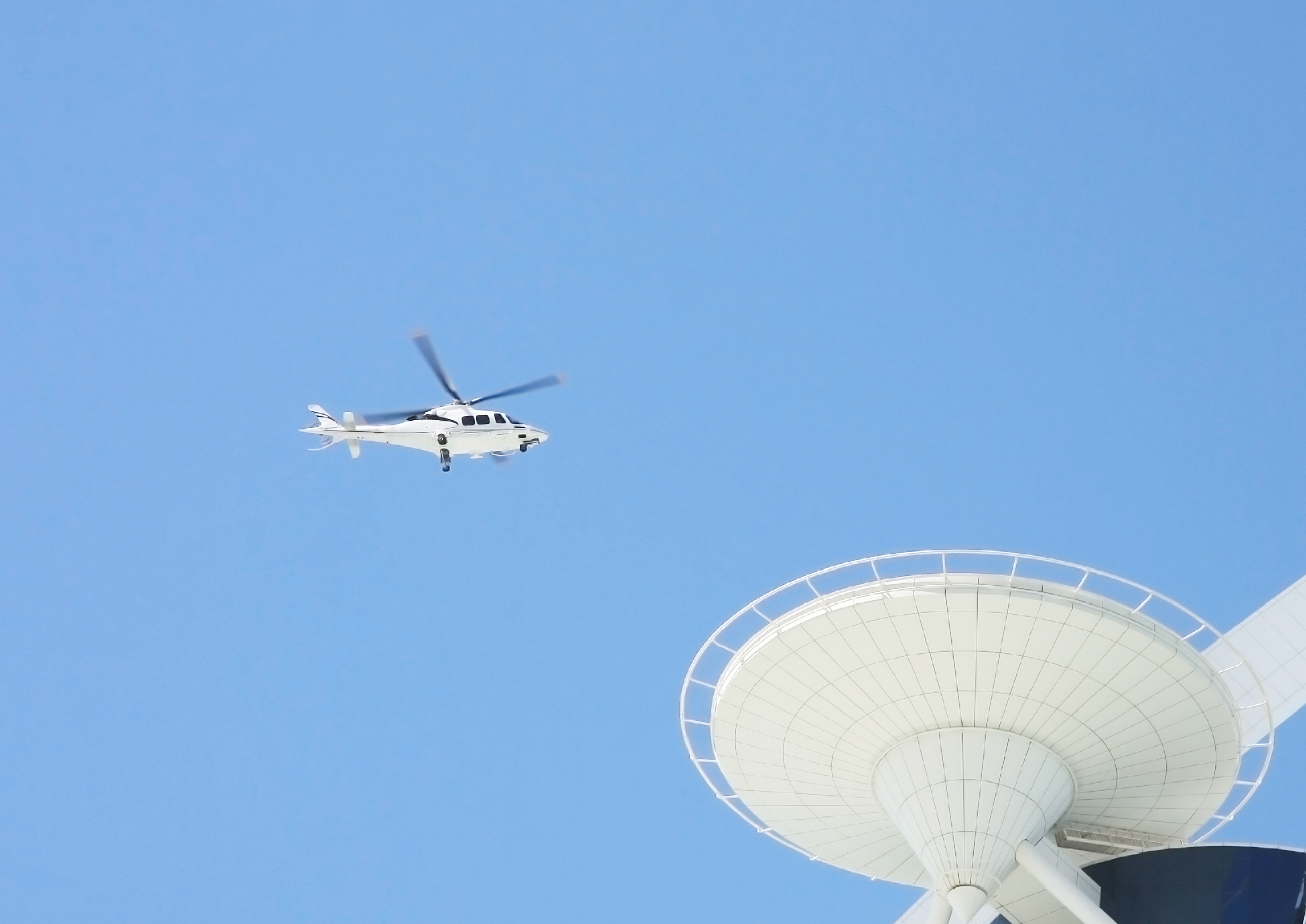 A white helicopter flies to a helicopter station on the roof of a high-rise building in Dubai. Rich life. VIP service in Dubai hotels.