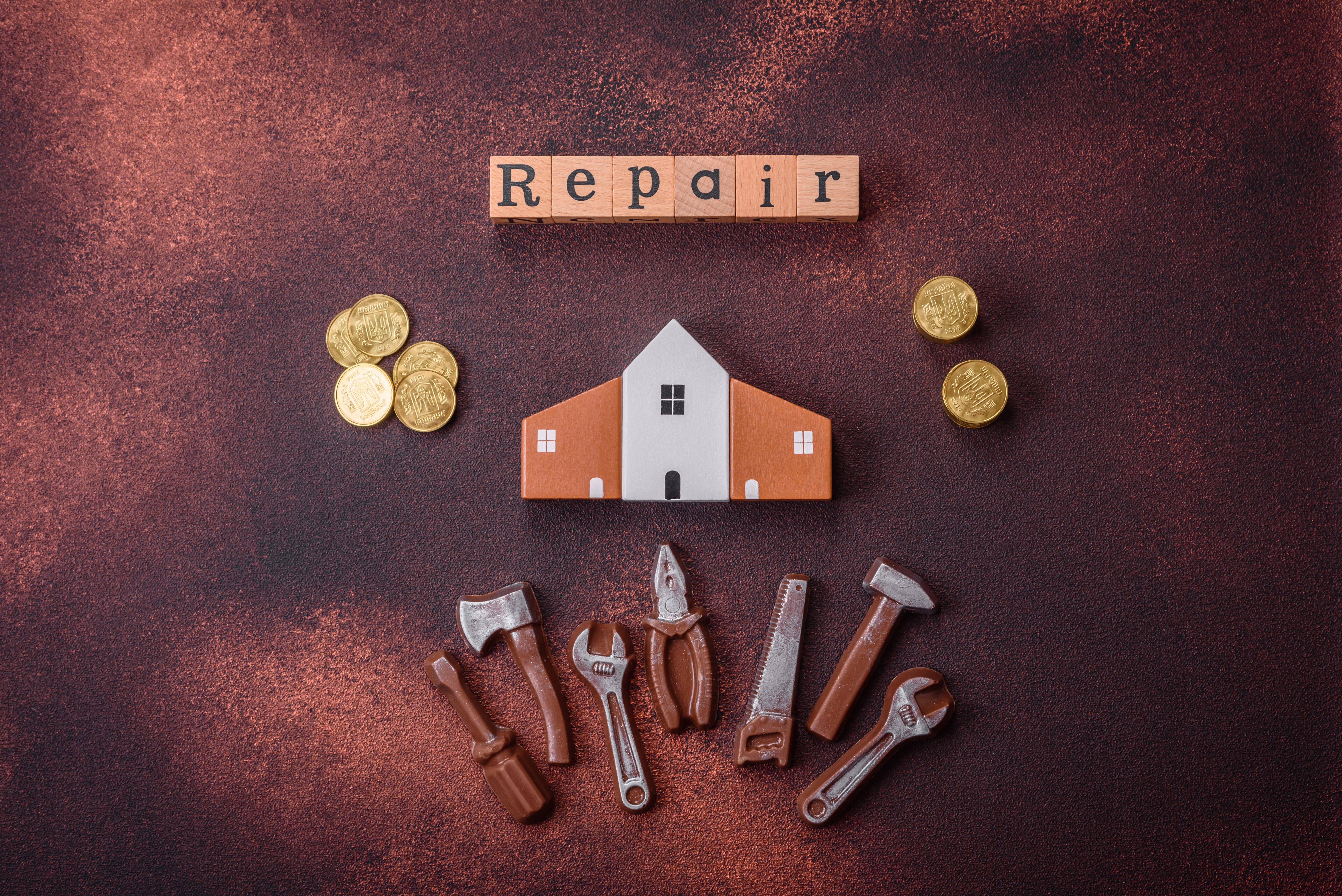 Repair or home improvement tools and a house model on a plain background