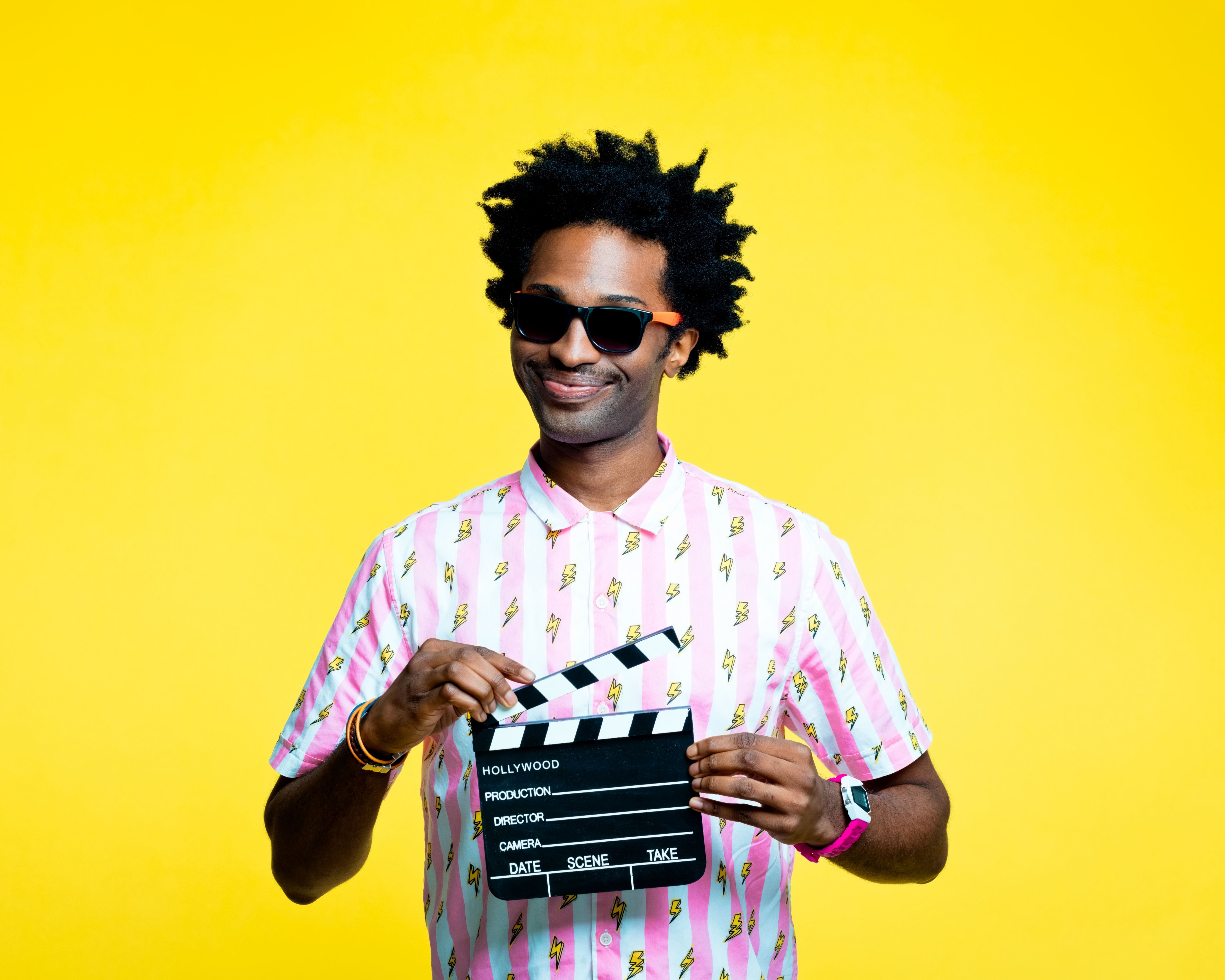 Smiling man holding film clapboard slate, studio portrait