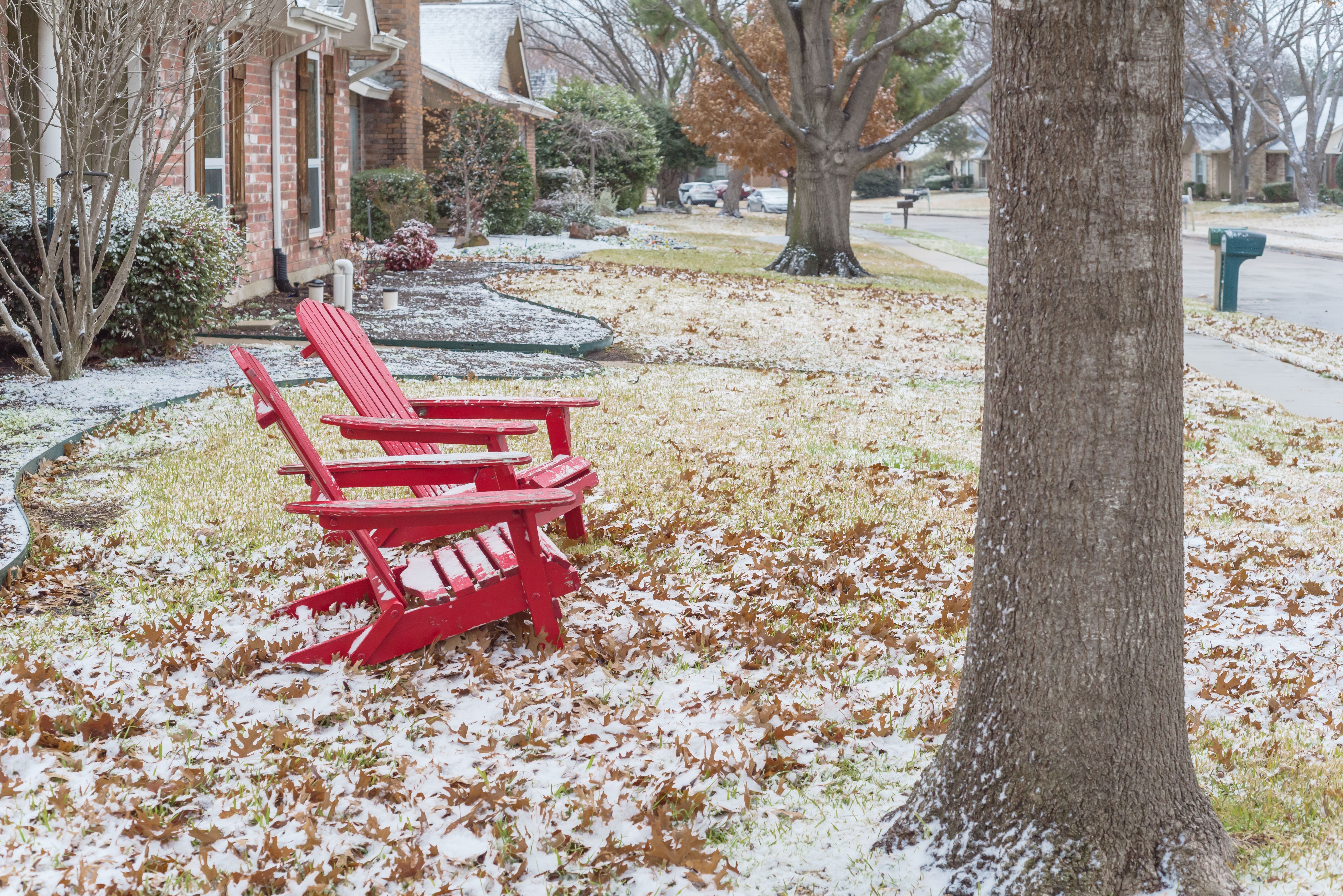 Red adirondack chairs with snow covered at front porch entrance of suburban house in Texas, USA Red adirondack chairs with snow covered at front porch entrance of suburban house in Texas, USA