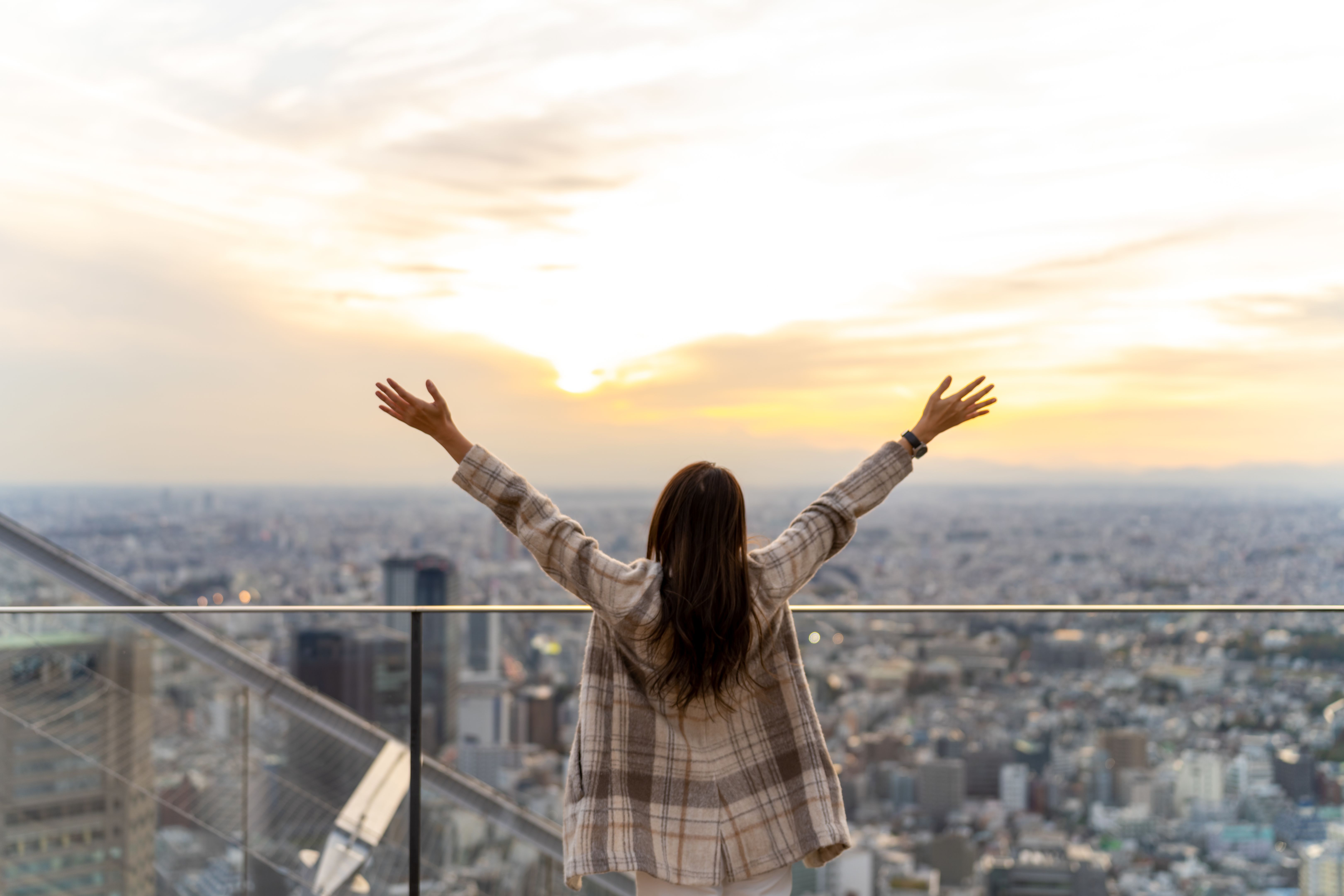 Portrait of Asian woman travel at skyscraper building rooftop in Tokyo city, Japan at sunset.