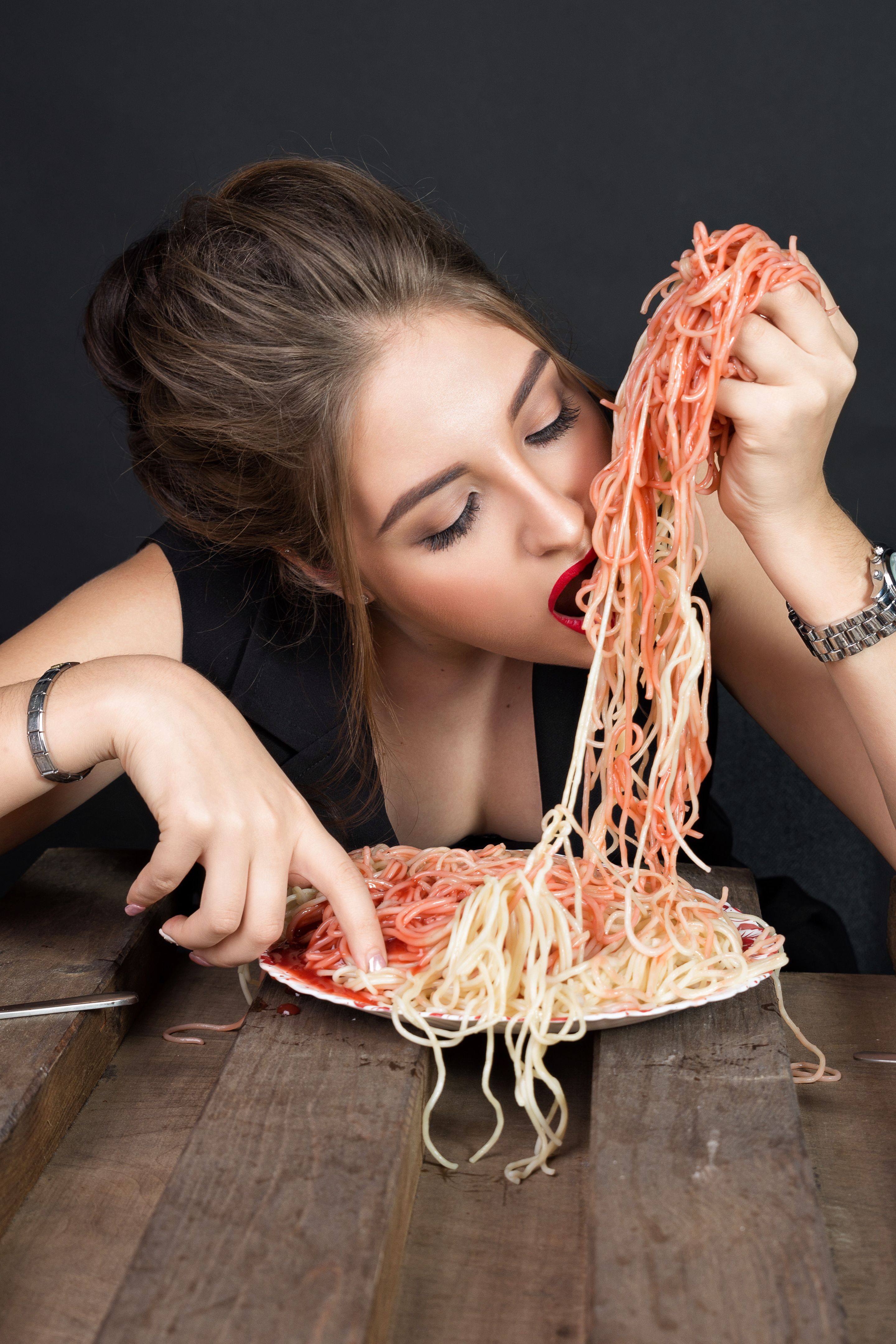 Woman eating spaghetti at wooden table