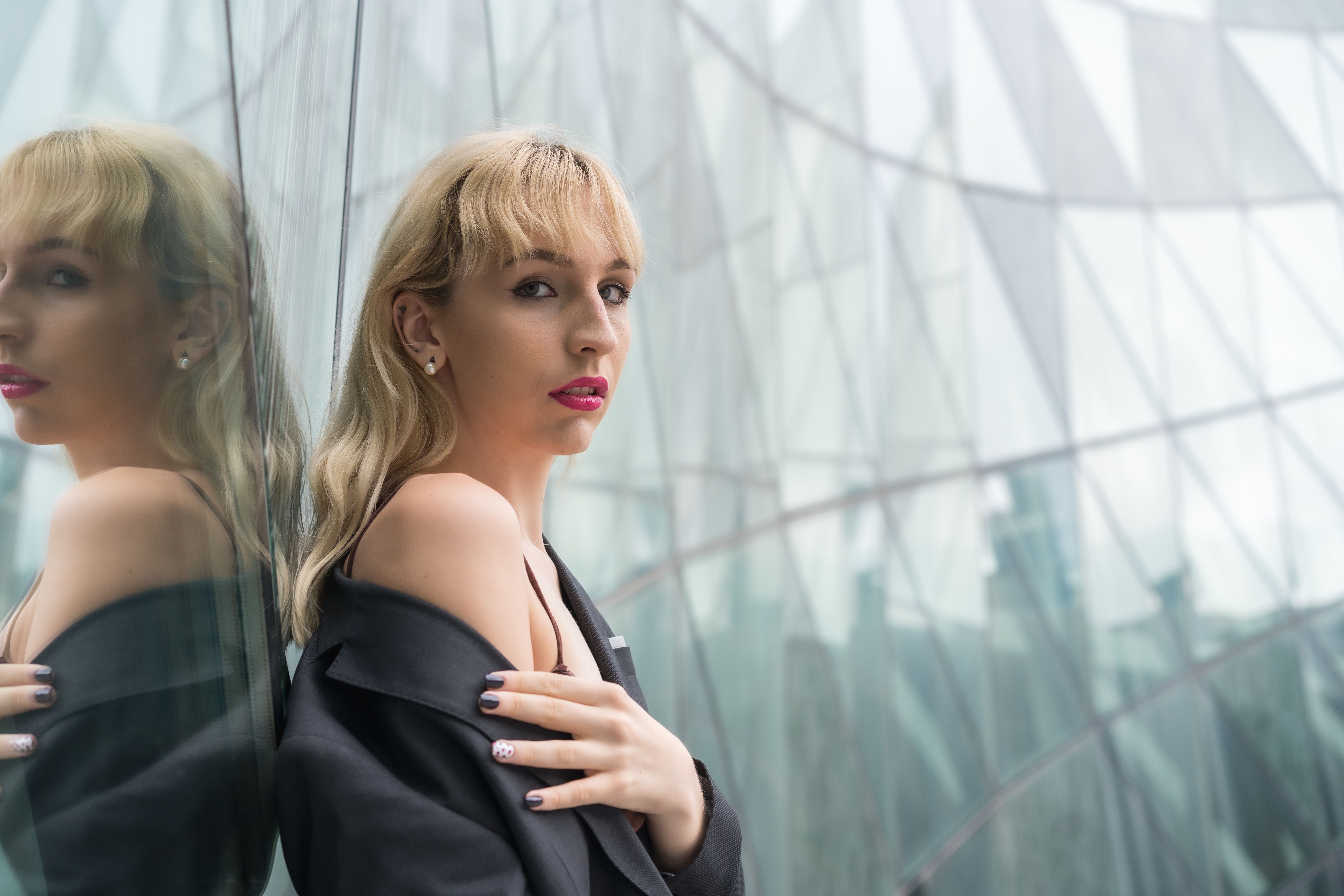 Attractive sexy Caucasian woman in a suit posing against a modern glass building