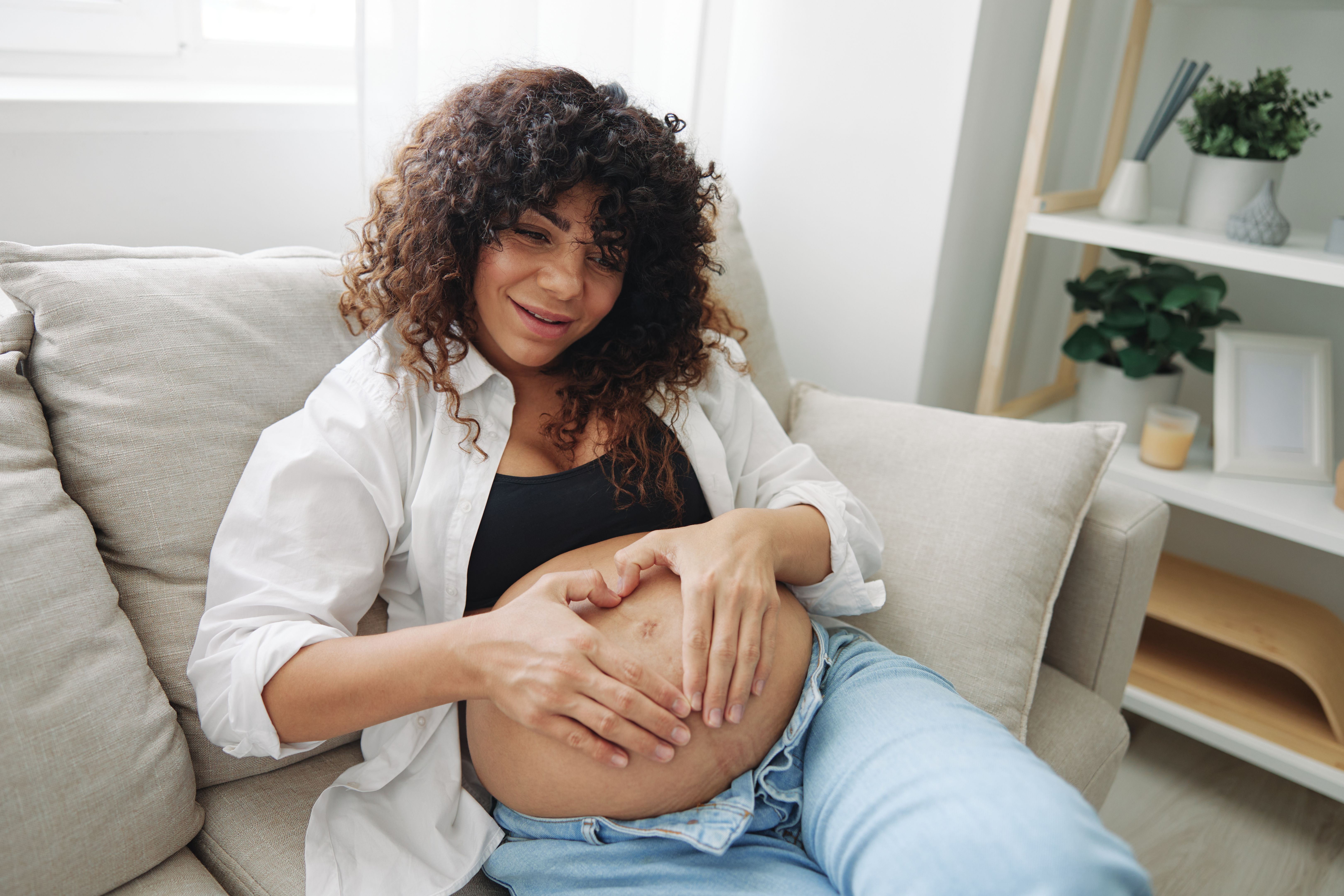 Pregnant woman smile and happiness lies on the couch freedom and strokes her belly with a baby in the last month of pregnancy, mother's day lifestyle Pregnant woman smile and happiness lies on the couch freedom and strokes her belly with a baby in the last month of pregnancy, mother's day lifestyle