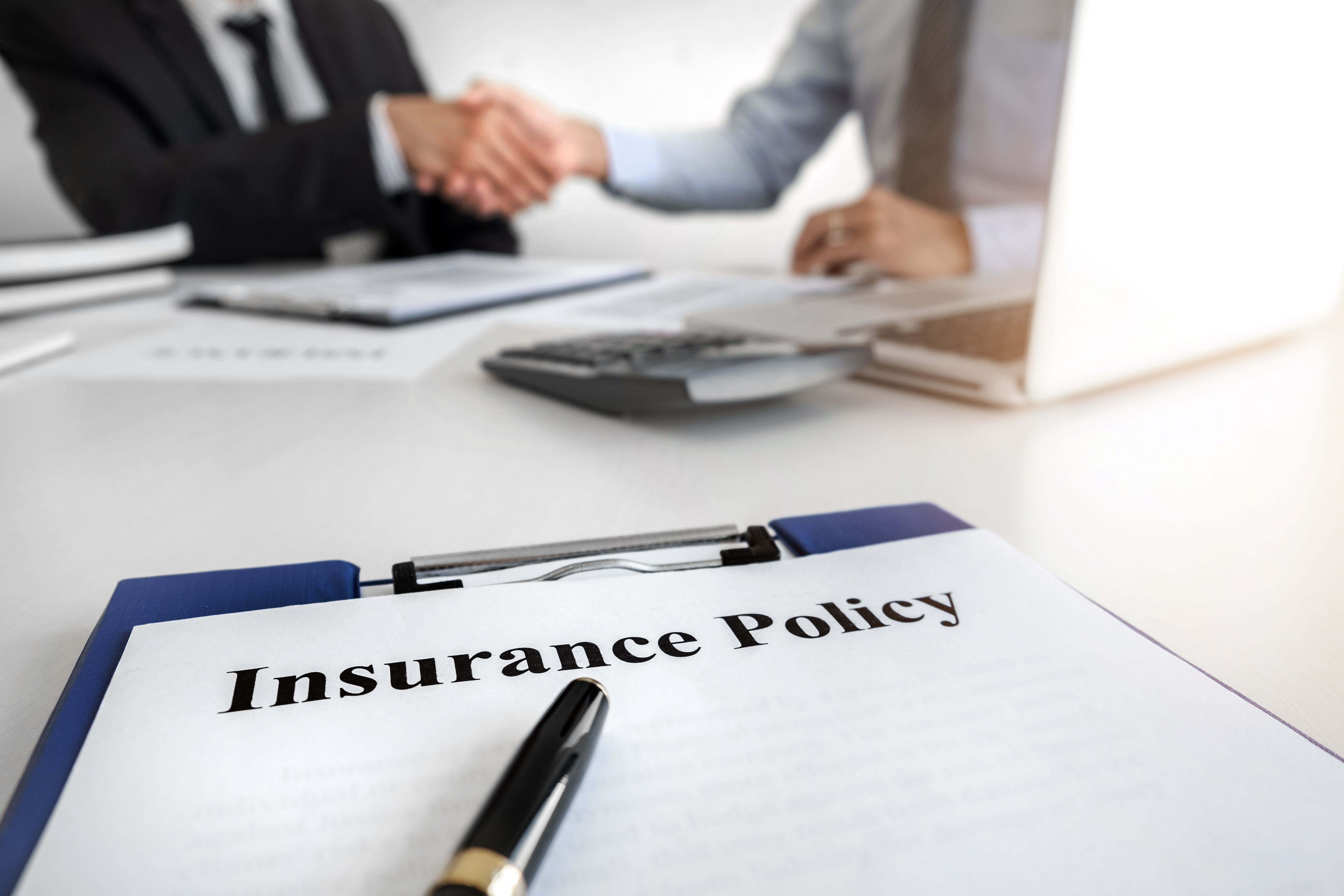 Insurance agent hand shaking insurance policy to customer in office room.