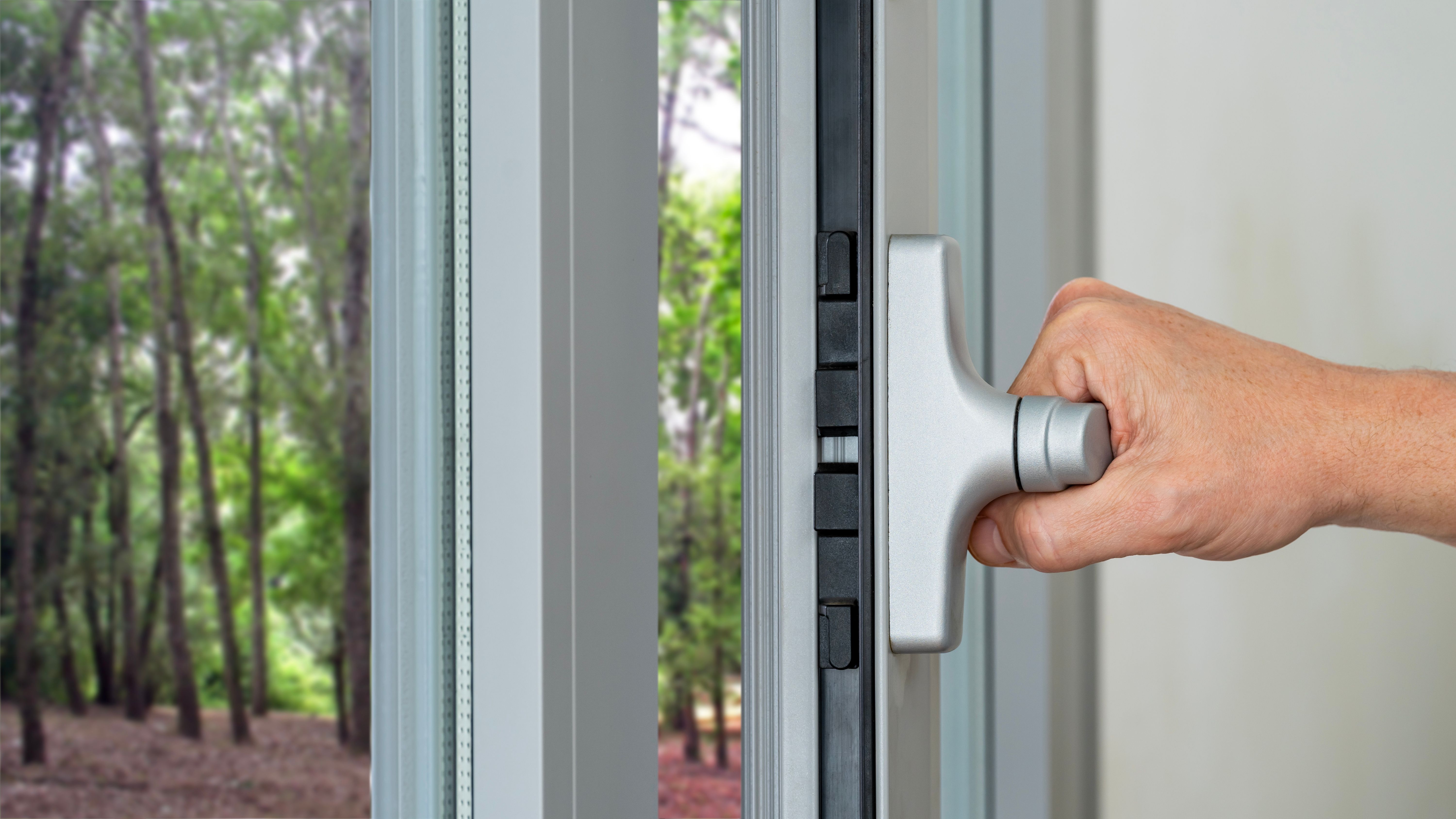 Close up of a male hand closing a double glazed window at home.