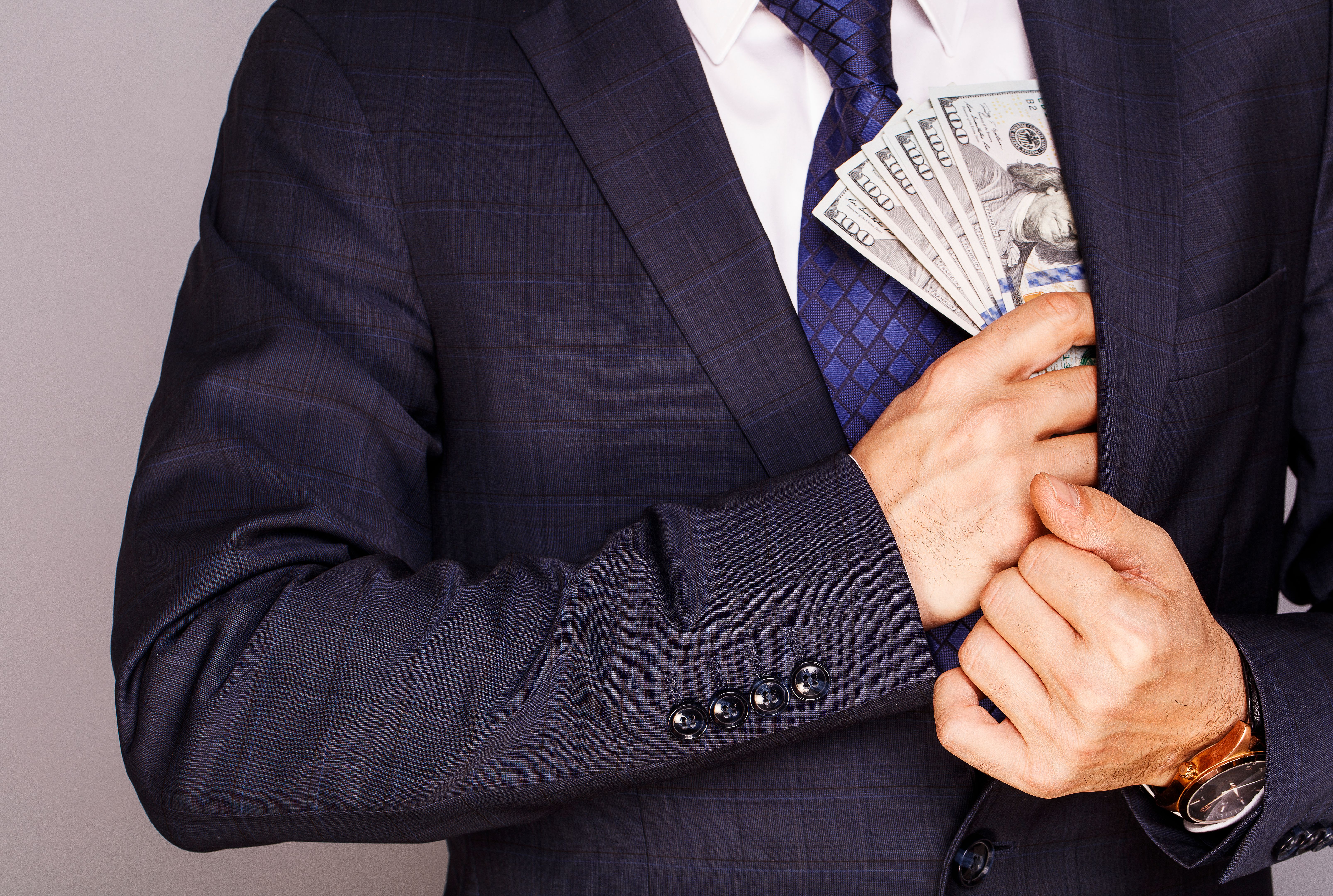 Businessman putting money in suit jacket pocket