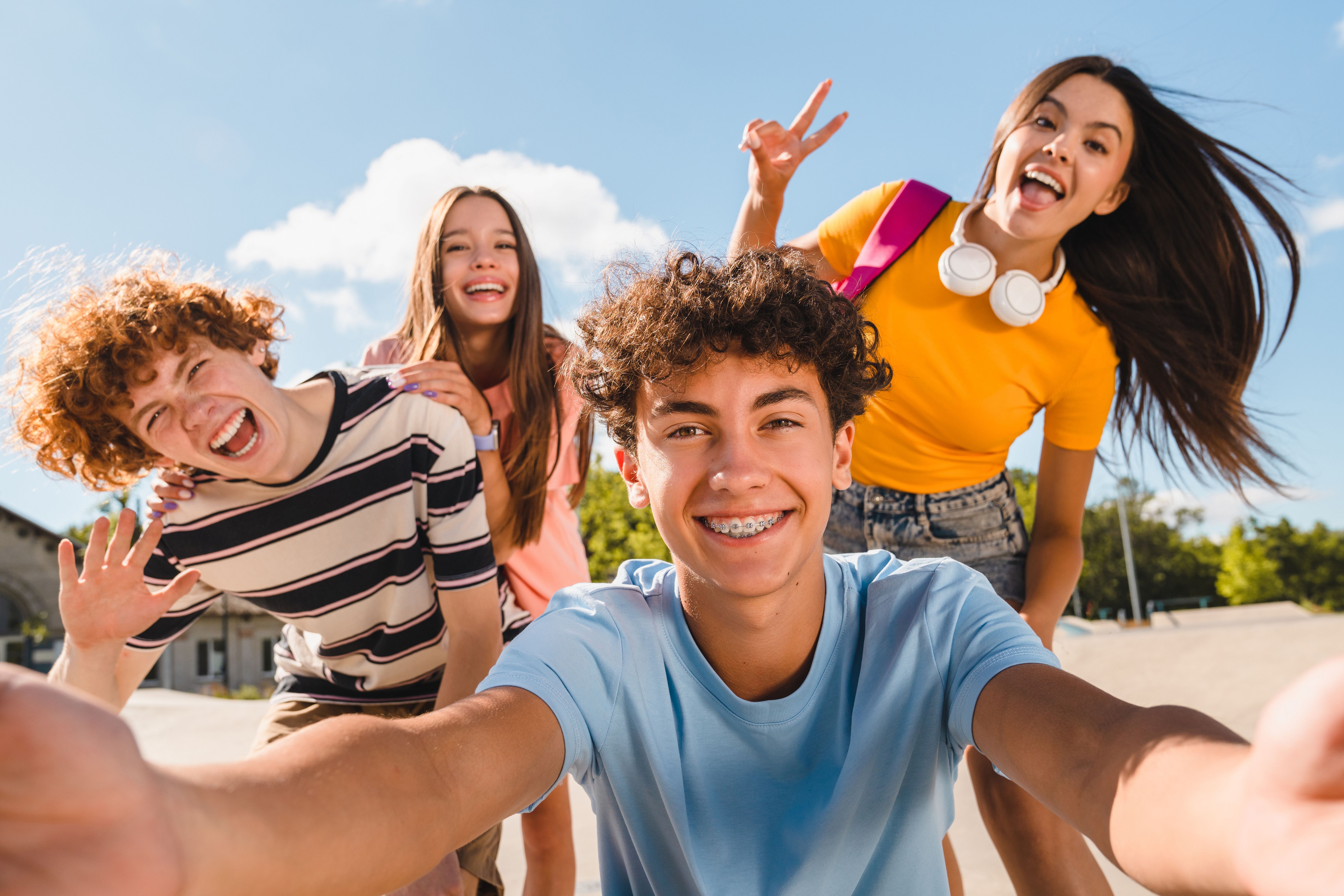Selfie shot of crazy young people having fun together spend summer weekend in skate park outside