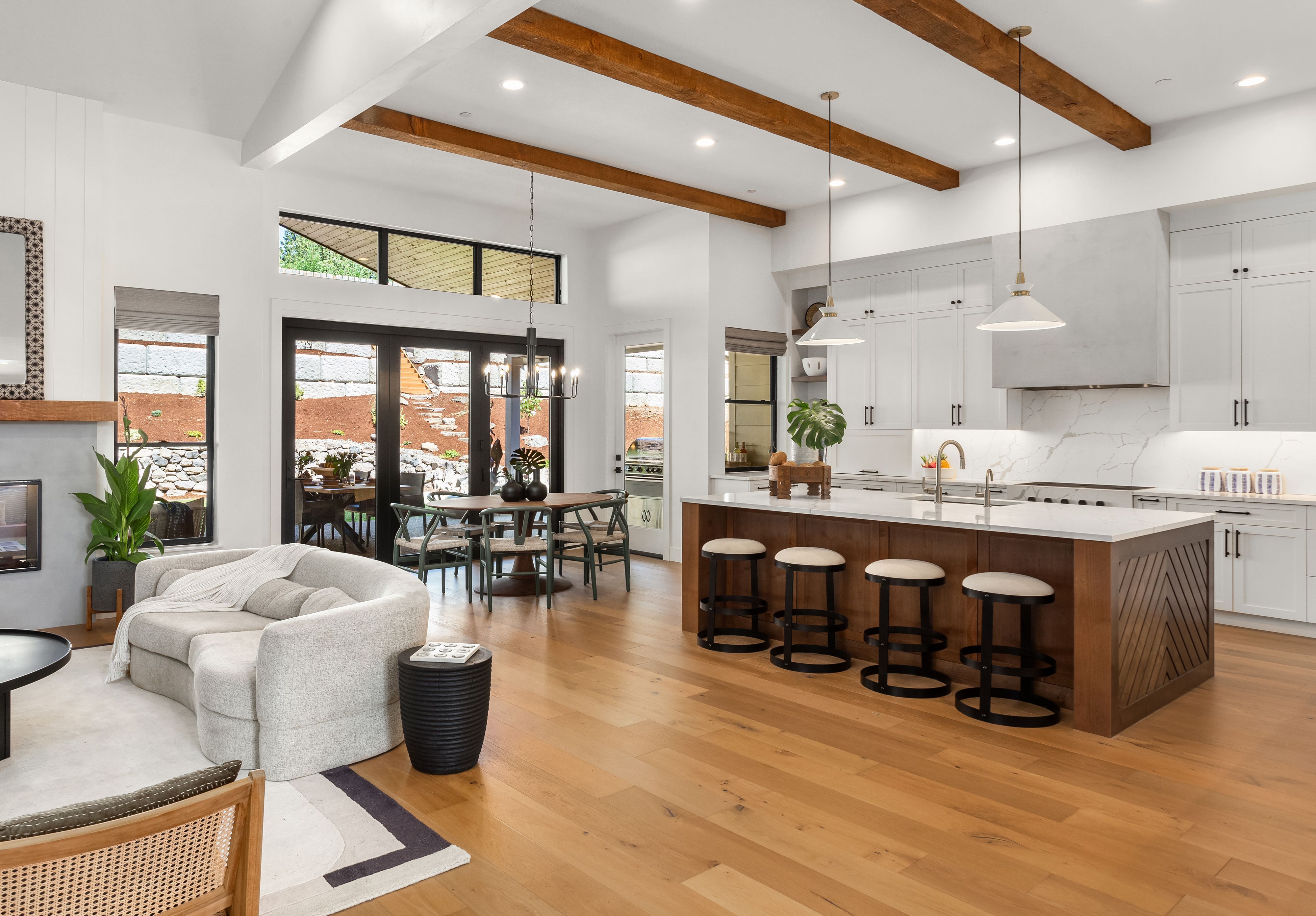 Beautiful living room and kitchen in new luxury home with white cabinets, wood beams, pendant lights and hardwood floors Beautiful living room and kitchen in new luxury home with white cabinets, wood beams, pendant lights and hardwood floors