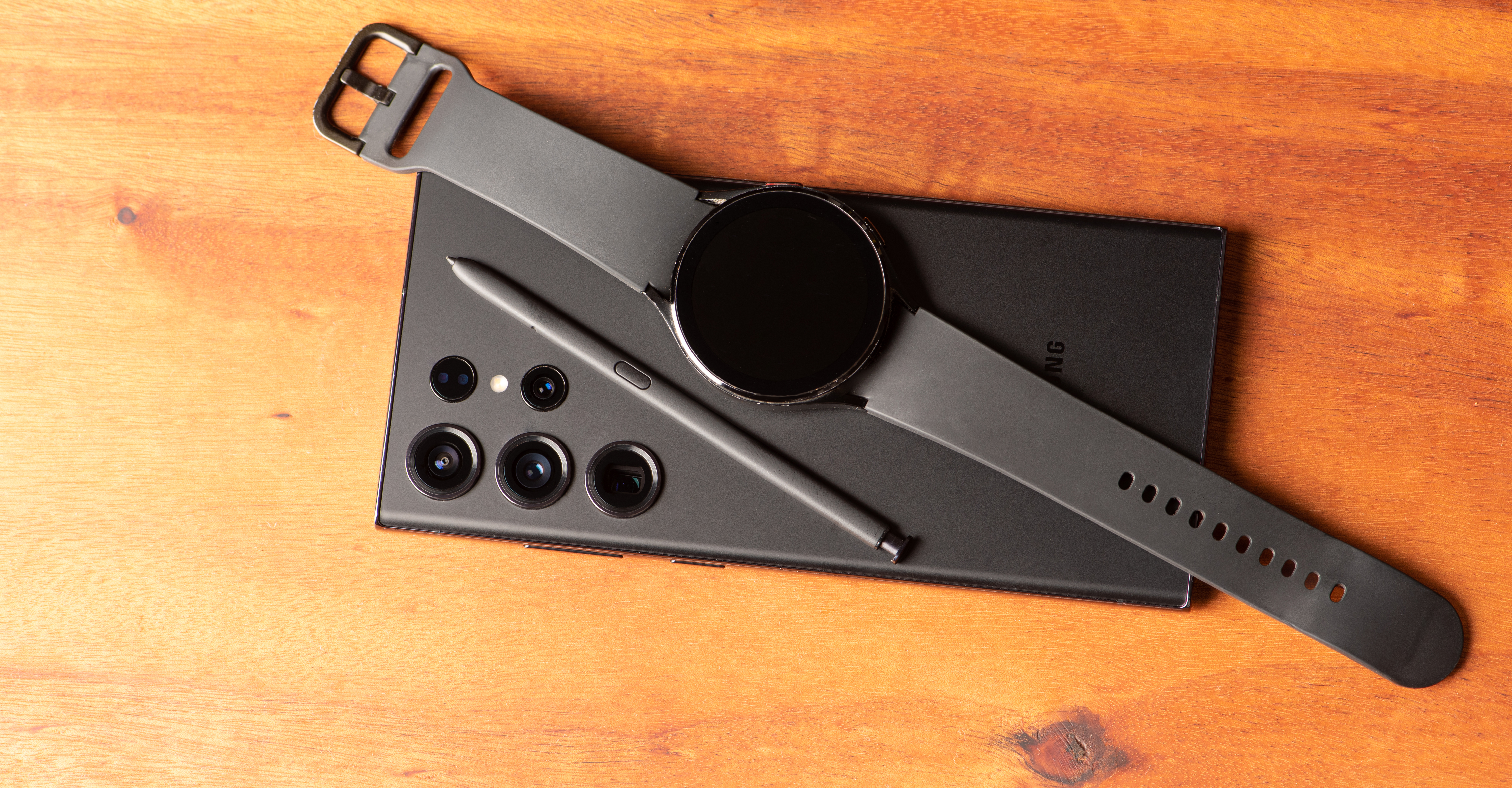 Samsung S23 ultra mobile phone with galaxy watch on it, over rustic wood, selective focus.