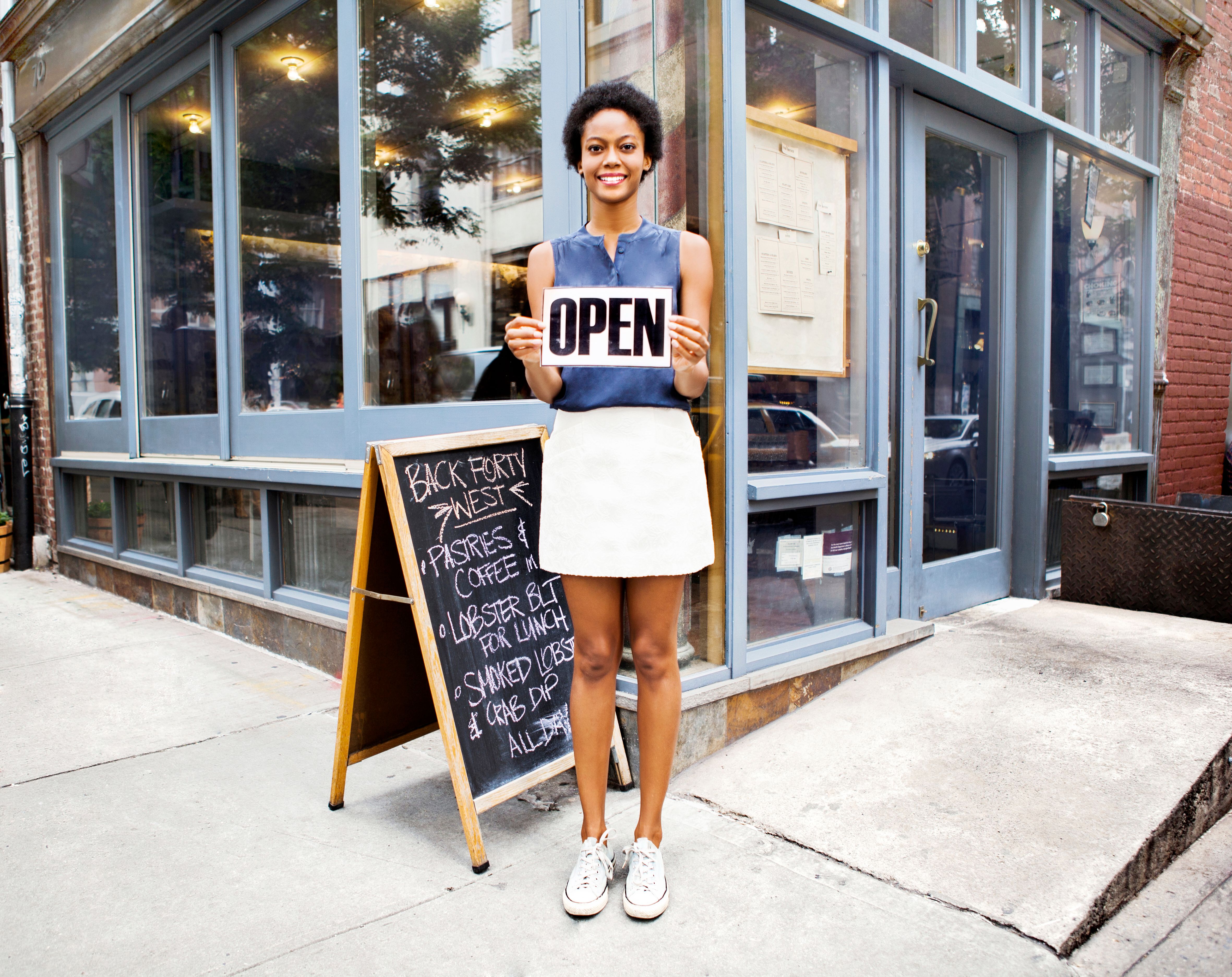 Woman outside of restaurant open for business Woman outside of restaurant open for business