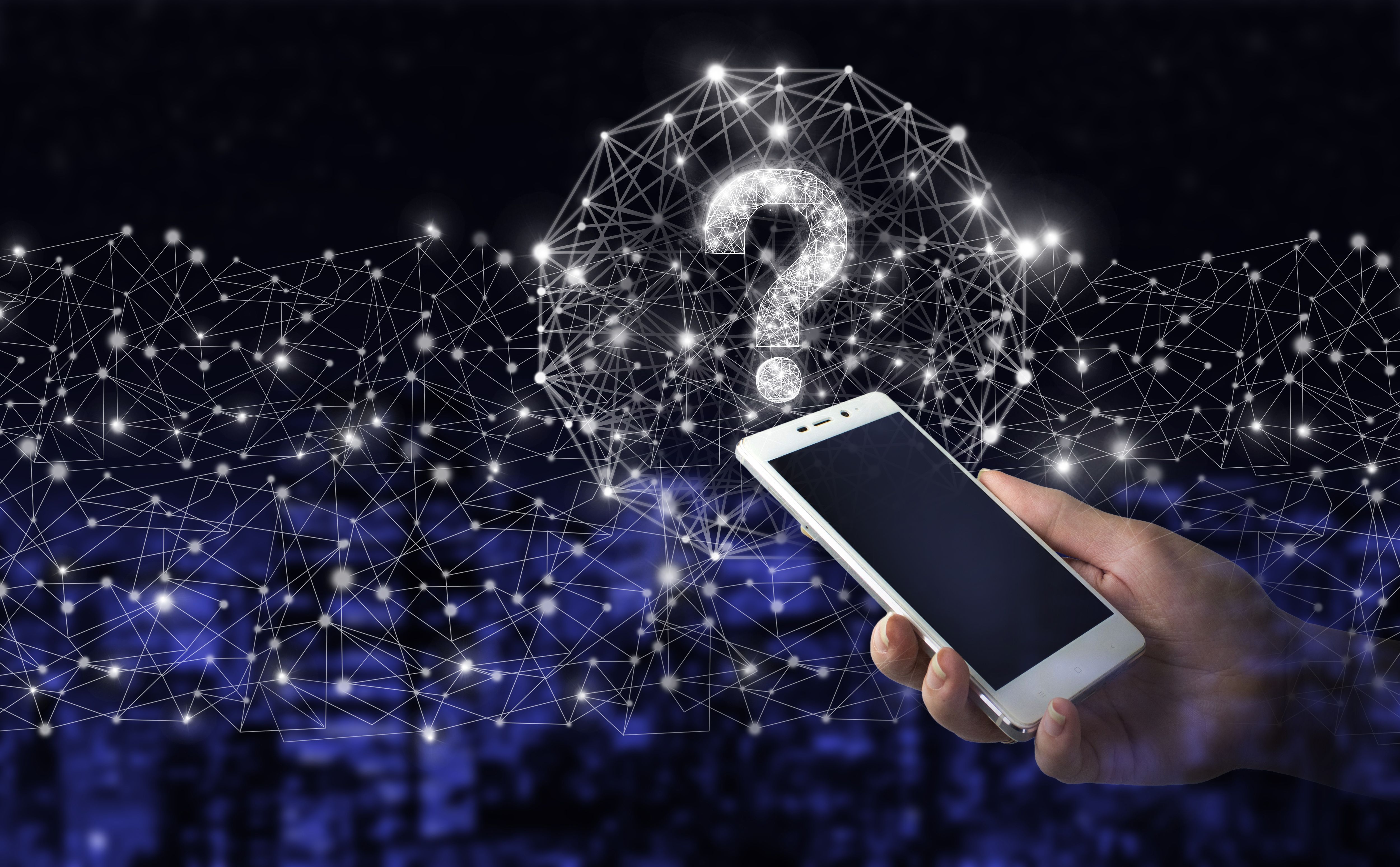 Hand hold white smartphone with digital hologram question mark sign on city dark blurred background.Business support concept. Problems and solutions. Hand hold white smartphone with digital hologram question mark sign on city dark blurred background.Business support concept. Problems and solutions.