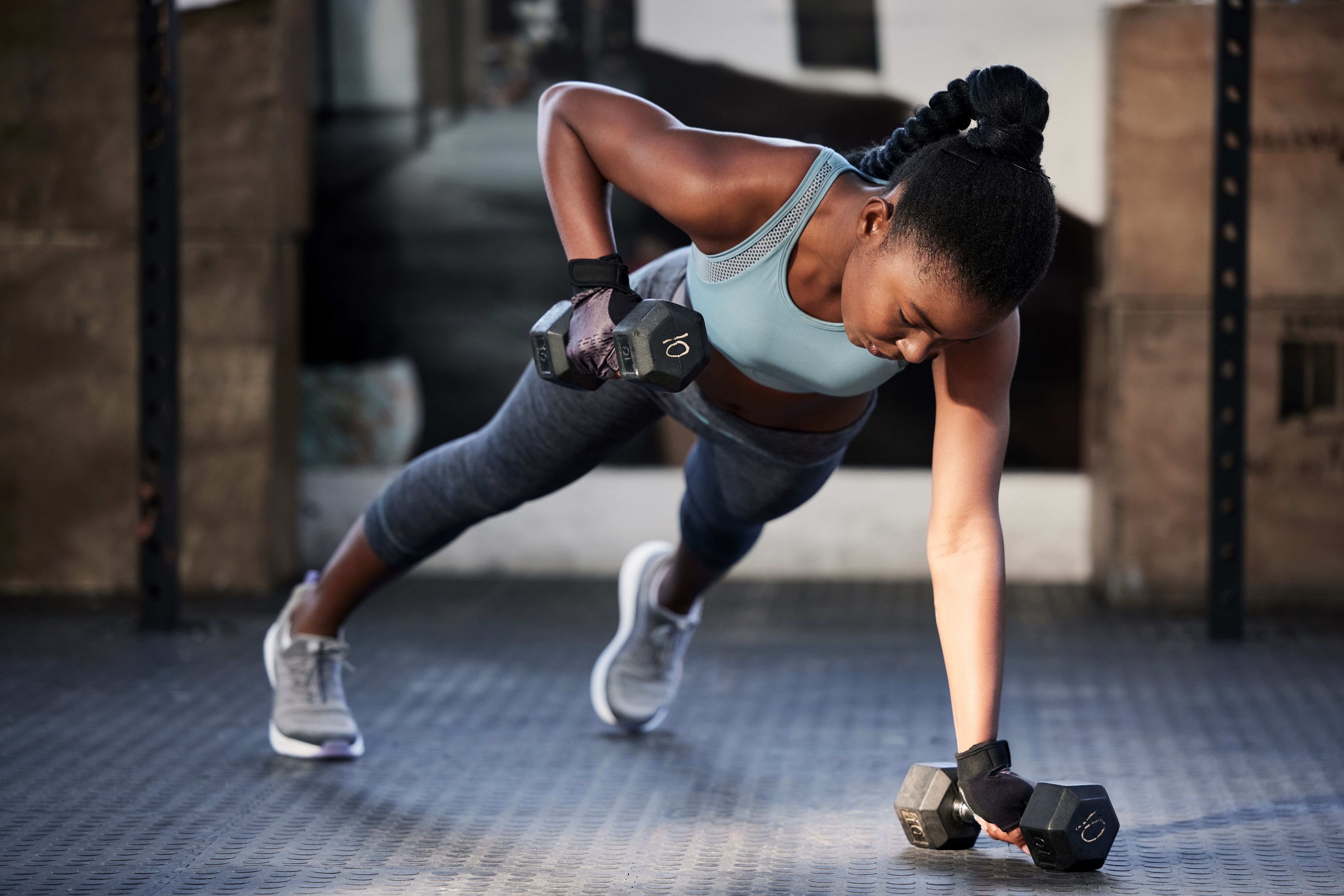 Shot of a fit young woman working out with dumbbells at the gym