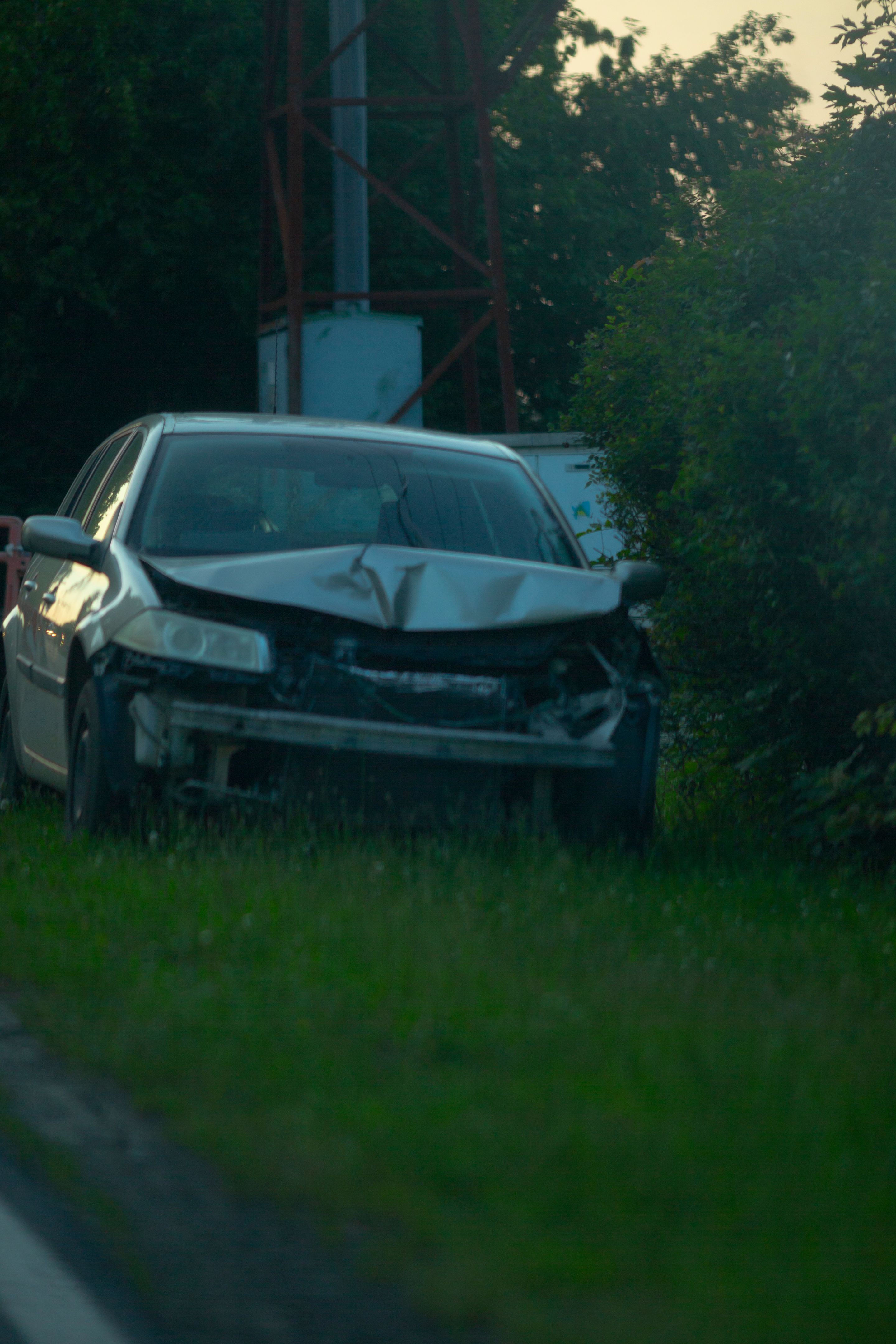 A damaged car is currently parked in the grass beside the road A damaged car is currently parked in the grass beside the road