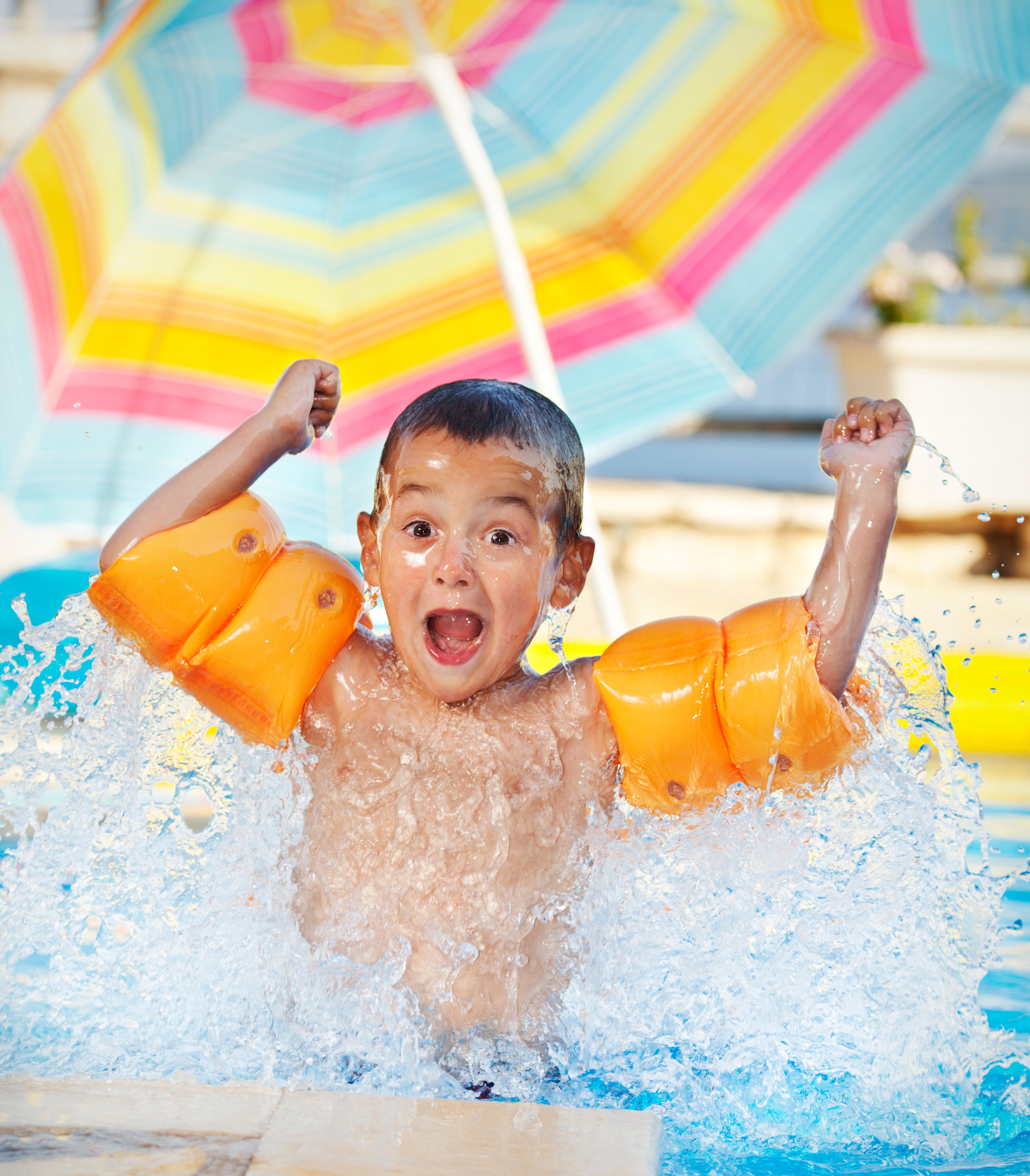 Playful boy splashing in the swimming pool