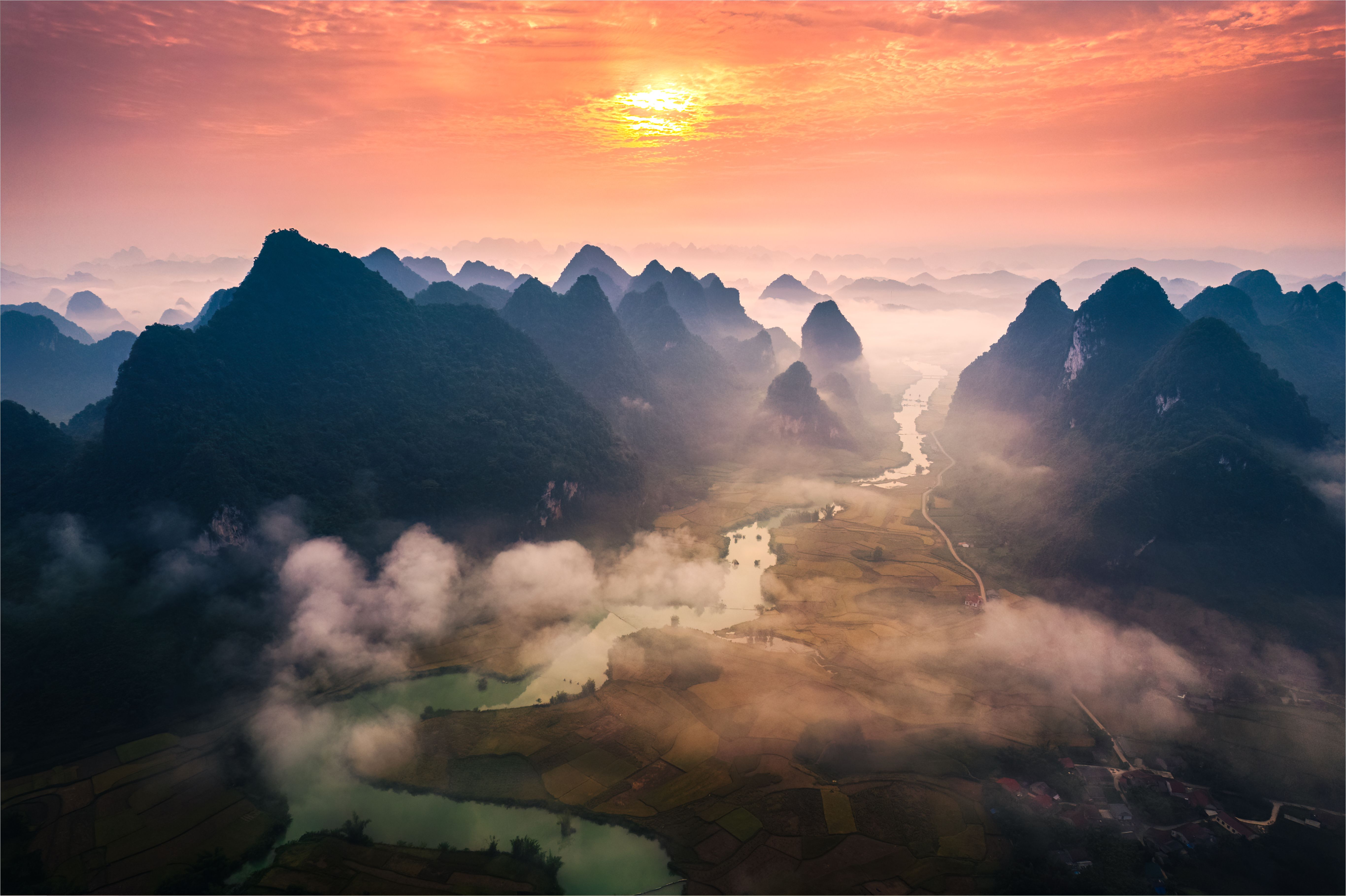 Sunrise over mountain range with foggy on rural village and river flows through in Phong Nam Valley at Vietnam