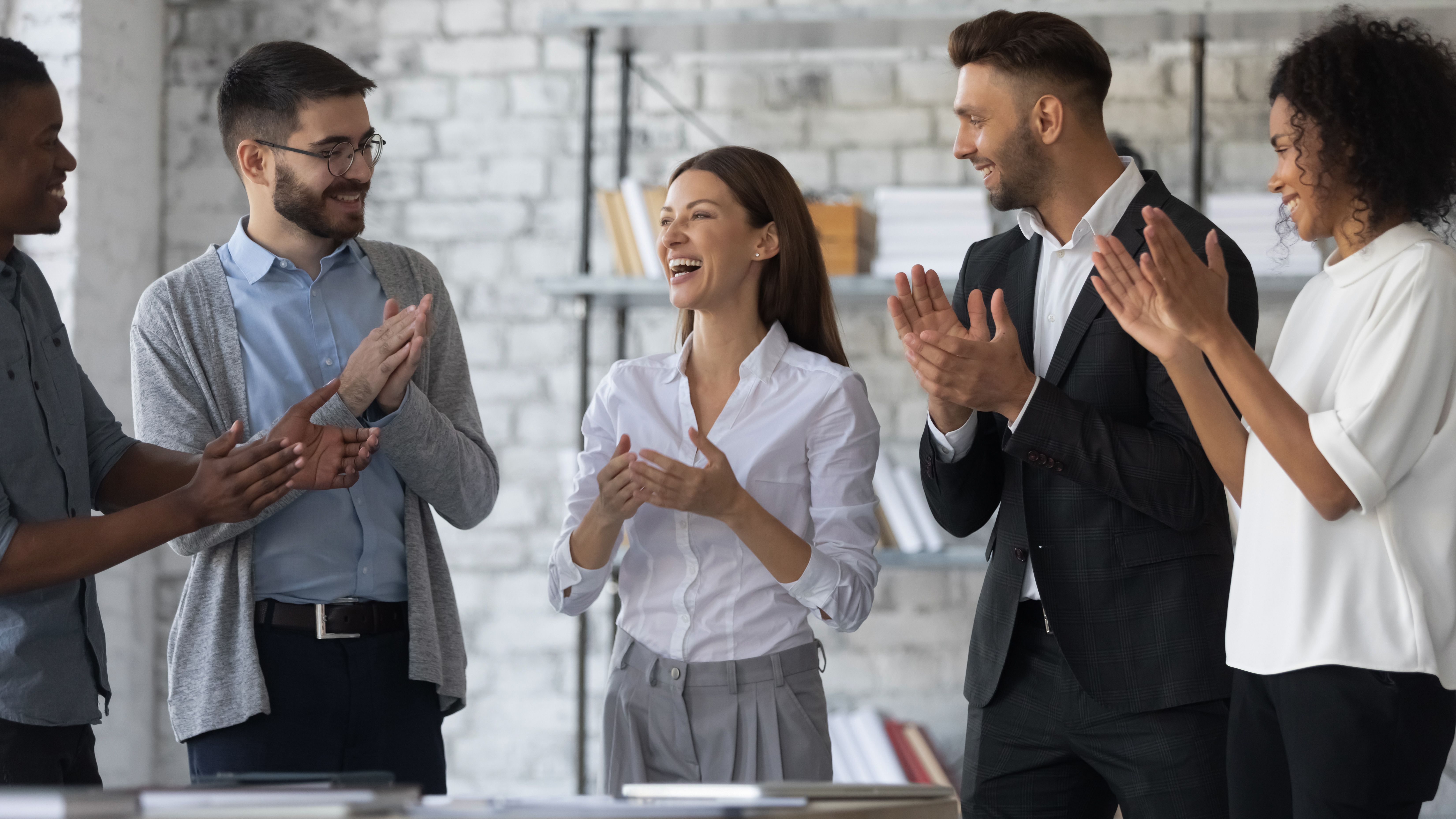 Friendly diverse employees congratulating businesswoman with business achievement Friendly diverse employees congratulating businesswoman with business achievement