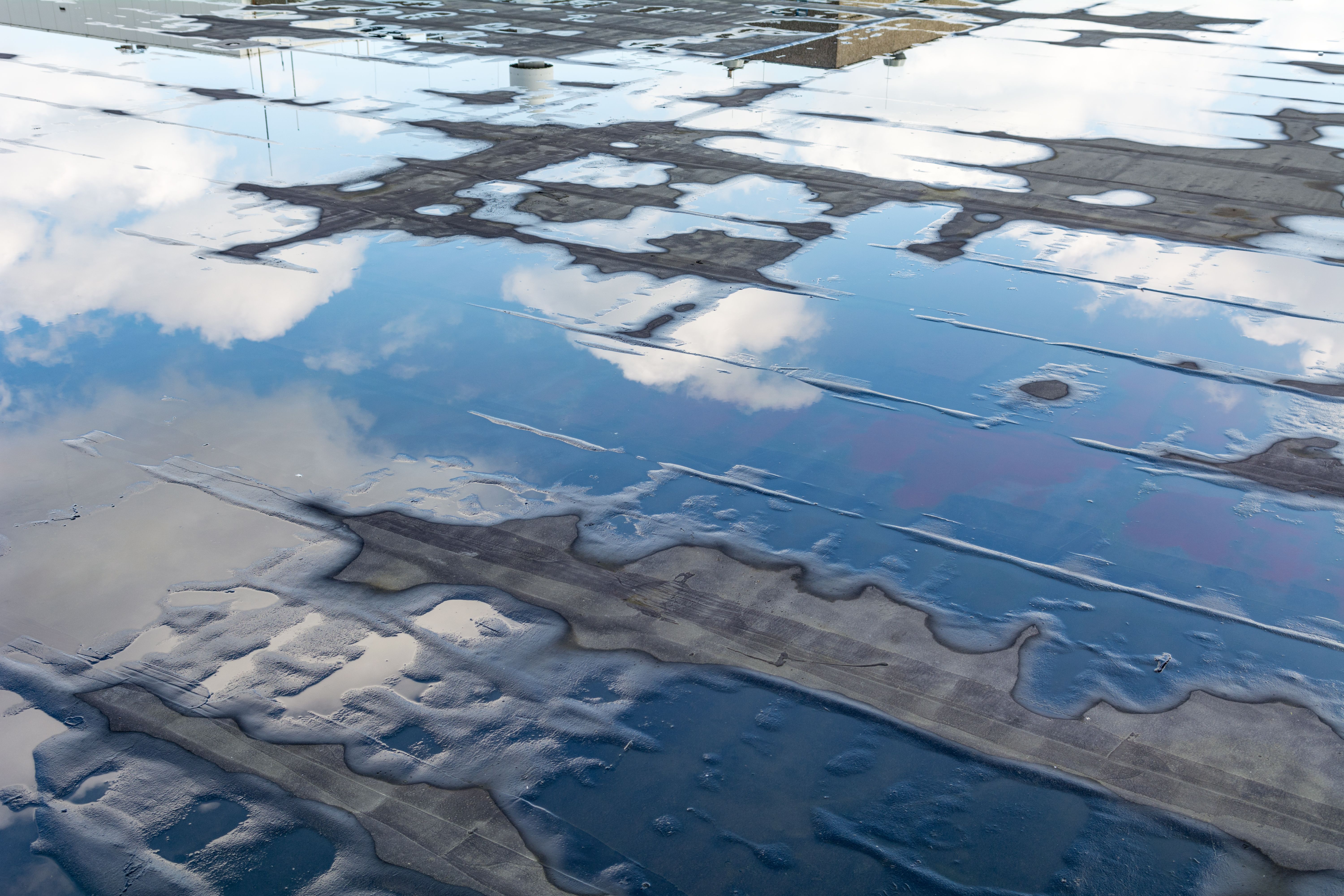 Flat roof with standing water and cloudscape reflection Flat roof with standing water and cloudscape reflection