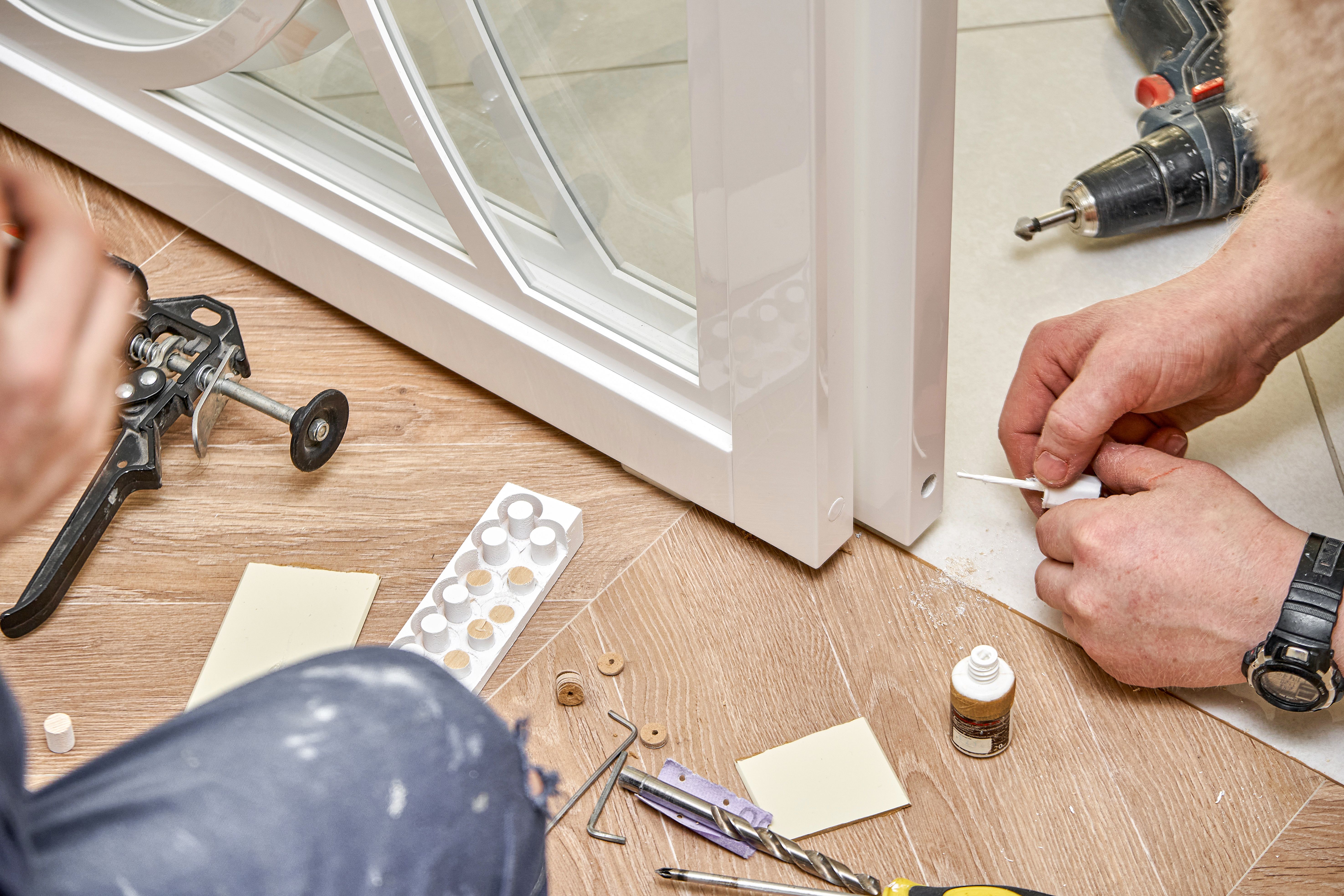 Sliding glass doors repair. Worker install end cap. White sliding glass doors with overlays decor