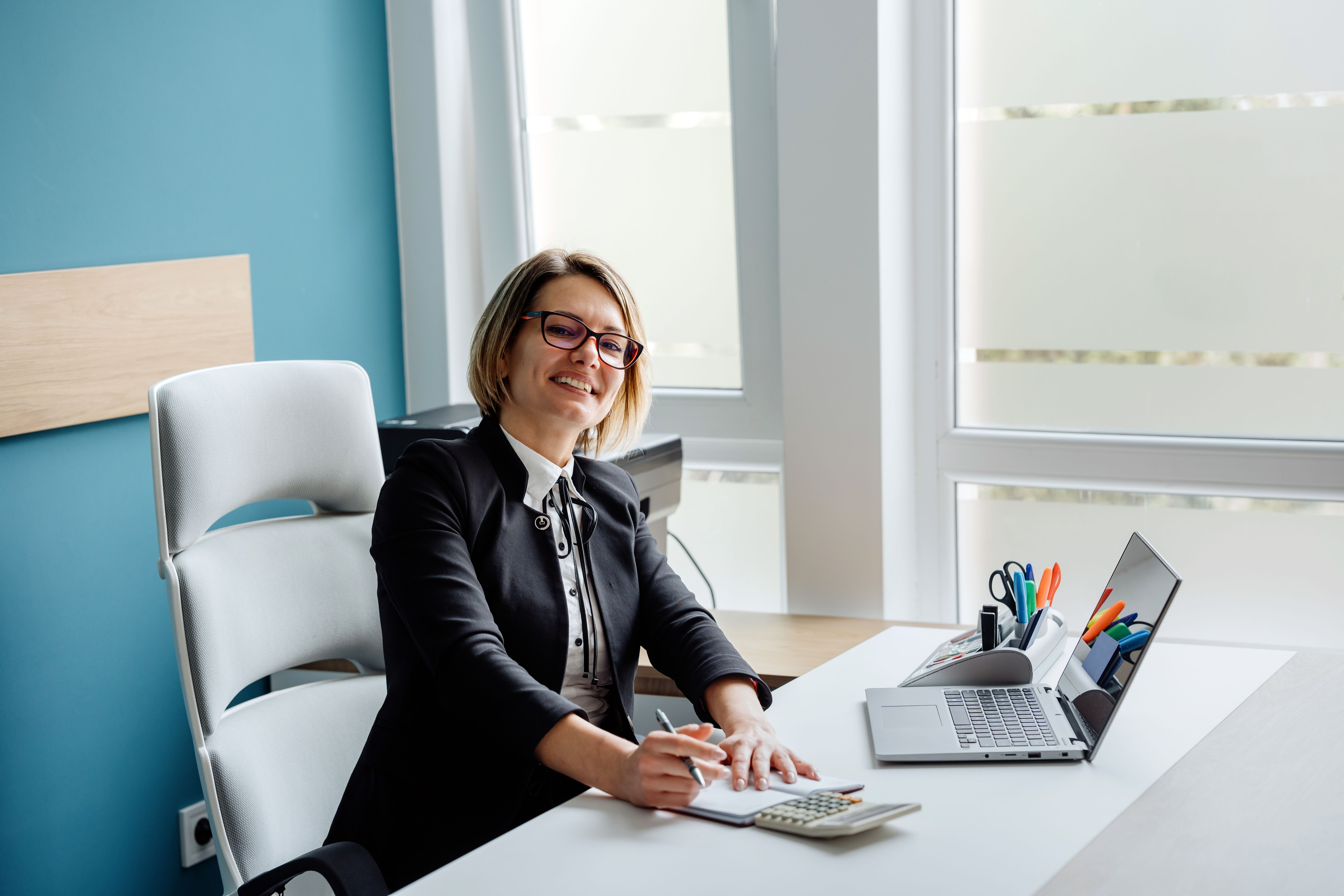 Portrait of a happy female accountant/businesswoman making financial calculations in her office Portrait of a happy female accountant/businesswoman making financial calculations in her office