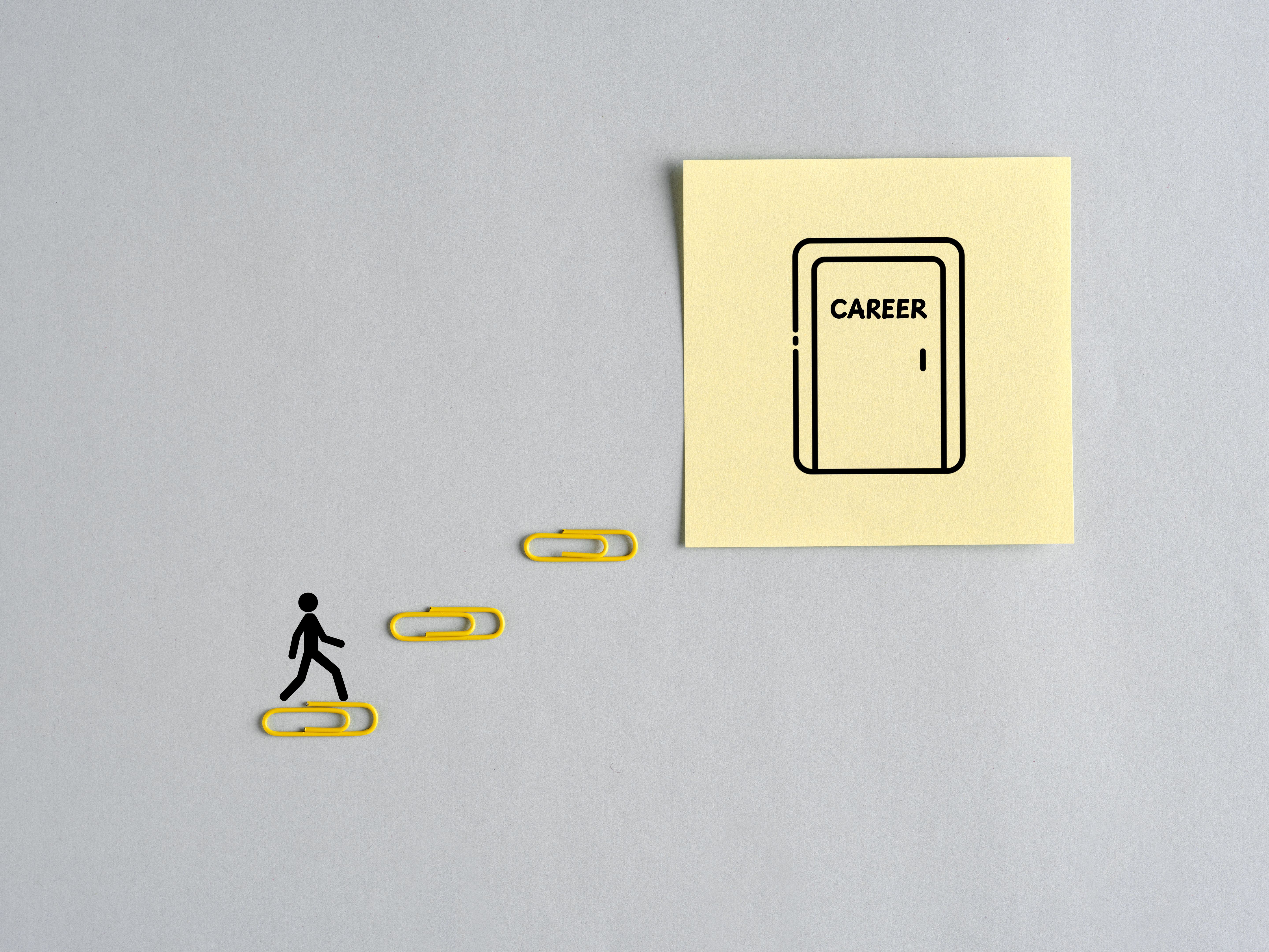 Businessman climbing stairs made of paper clips pursuing career path