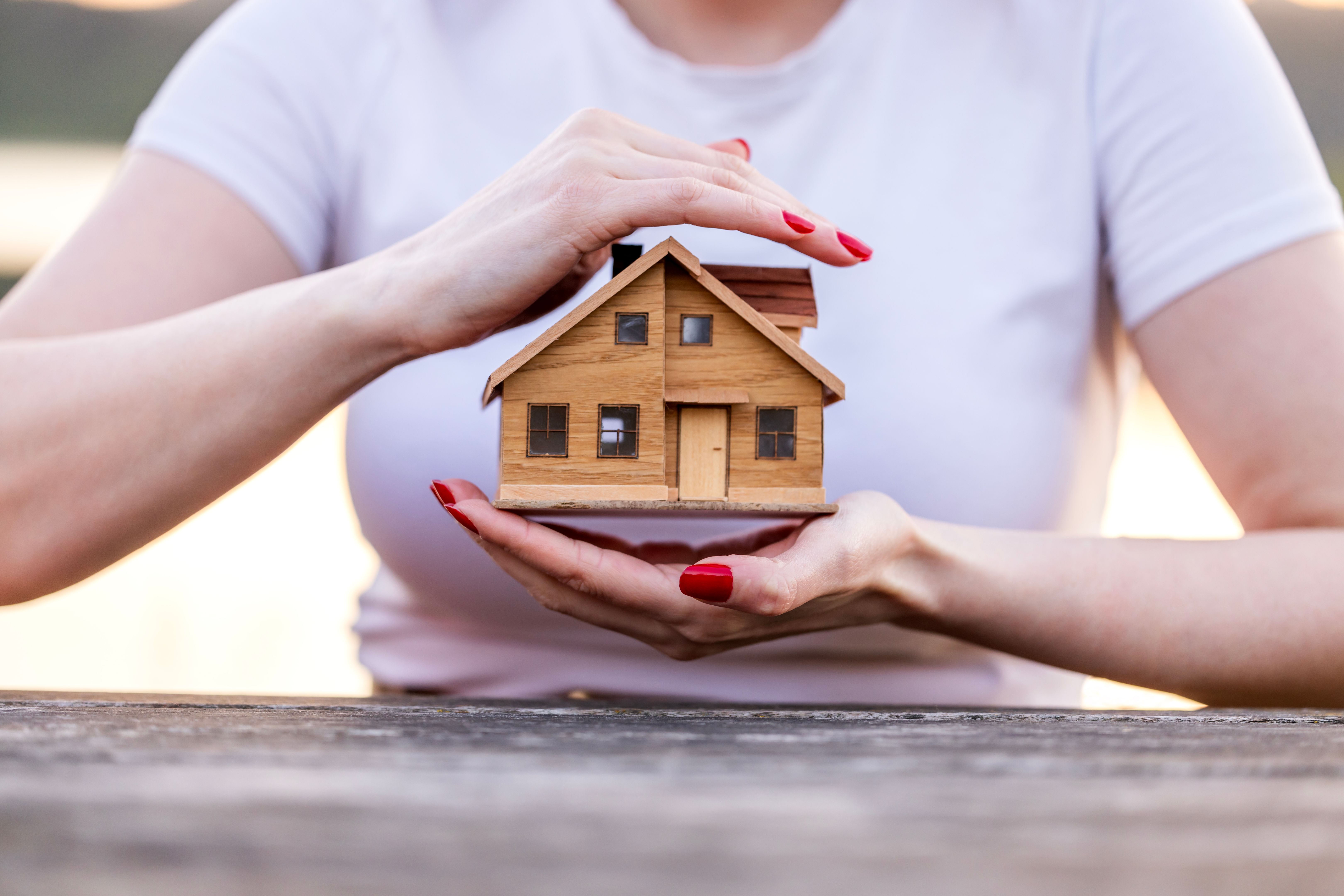 Woman showing model of house that she plans to insurance concept