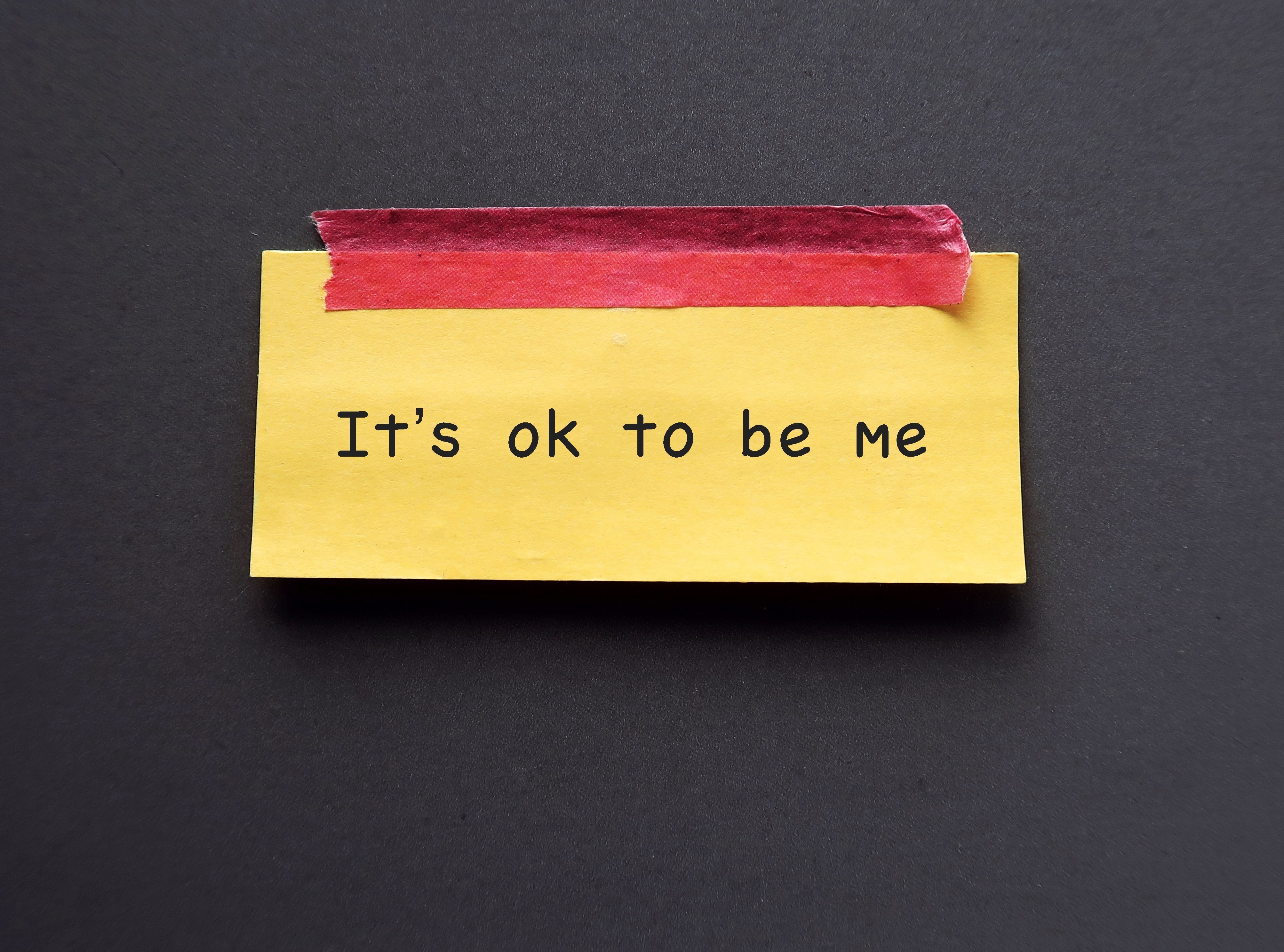 Yellow note stick on blue background with text 'Its ok to be me' concept of using positive sentences mantra affirmation will immediately change the way we think and boost self esteem
