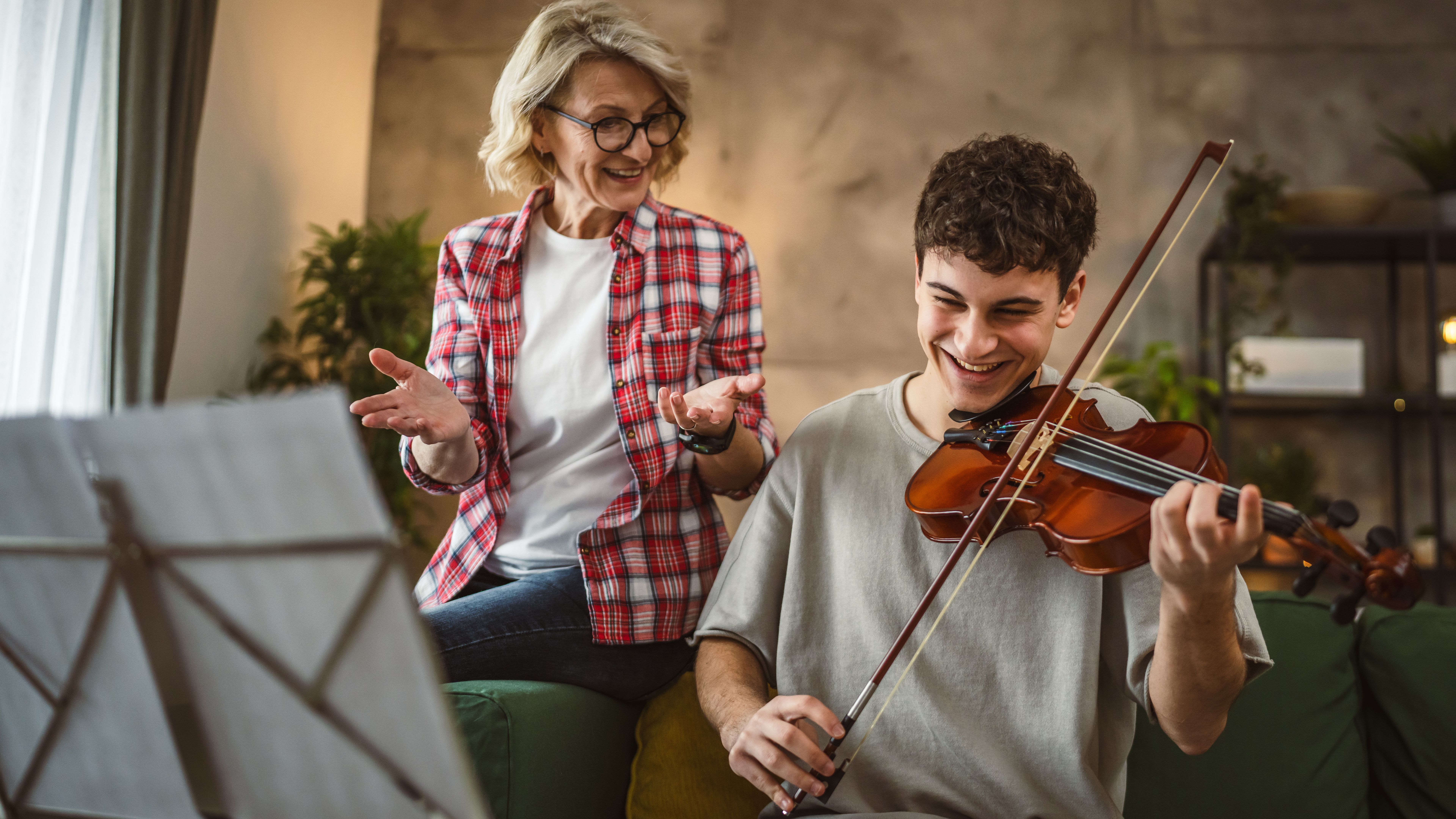 Young man learn how to play violin under instruction mature professor