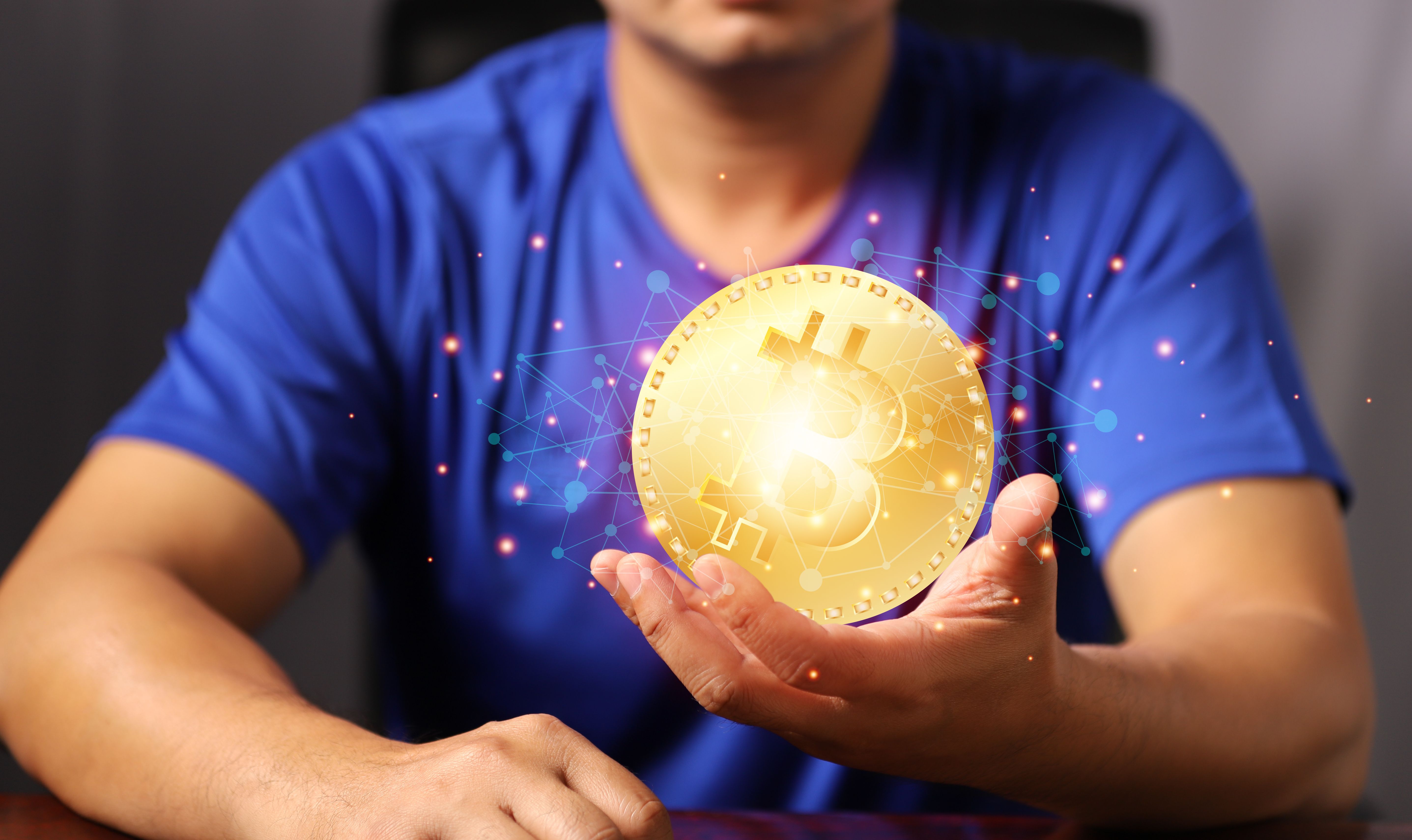 Blockchain technology and network concept. Man holding bitcoin hand with icons network connection on blue security and digital connection background.