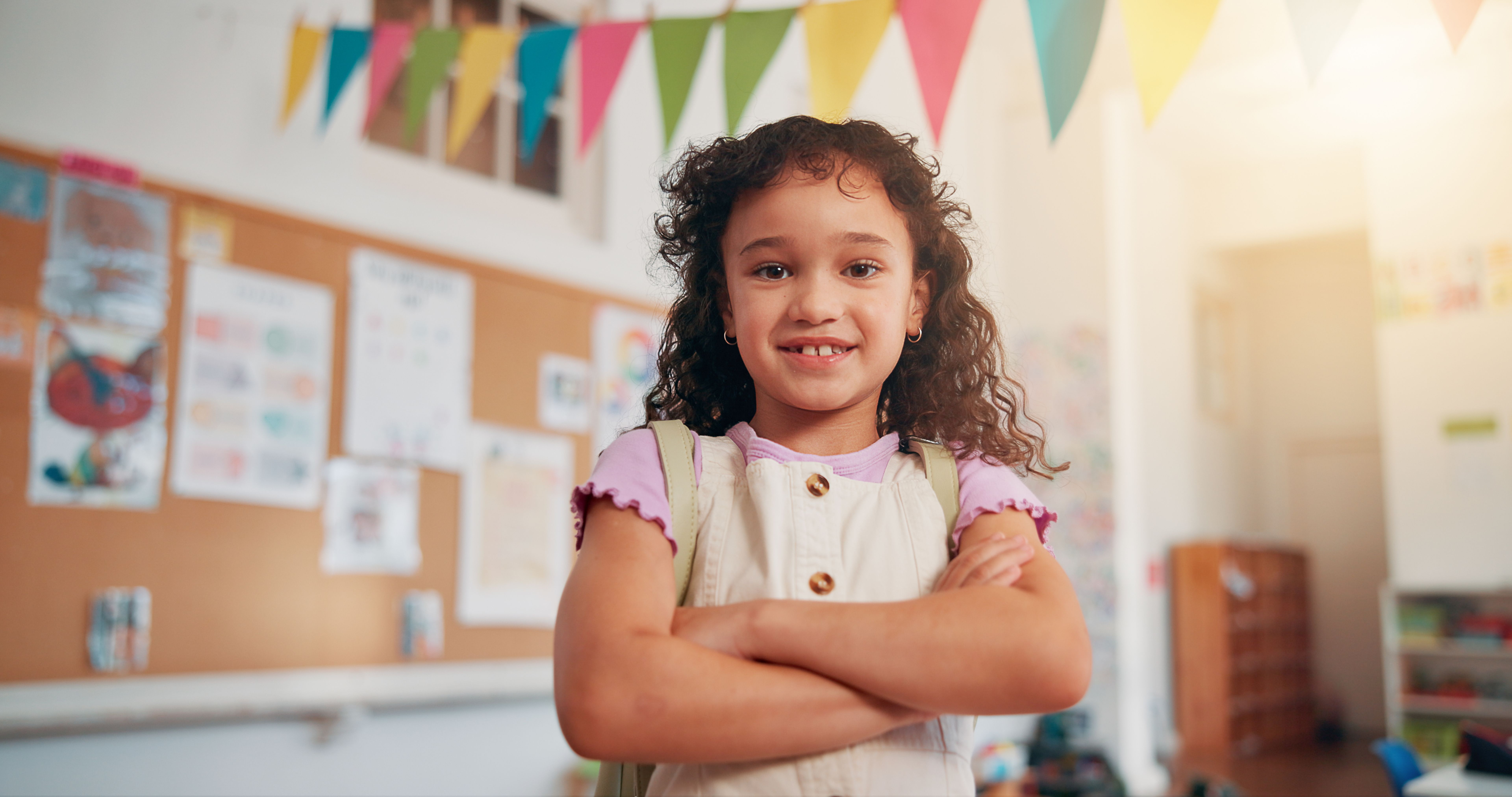 Arms crossed, youth and education with girl in classroom for learning, future and student. Scholarship, academy and growth with portrait of kid in school for child development, knowledge and lesson
